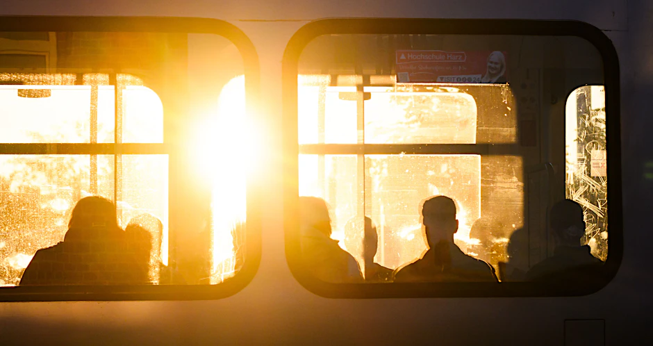 Fahrgäste sitzen bei Sonnenaufgang in einer S-Bahn.