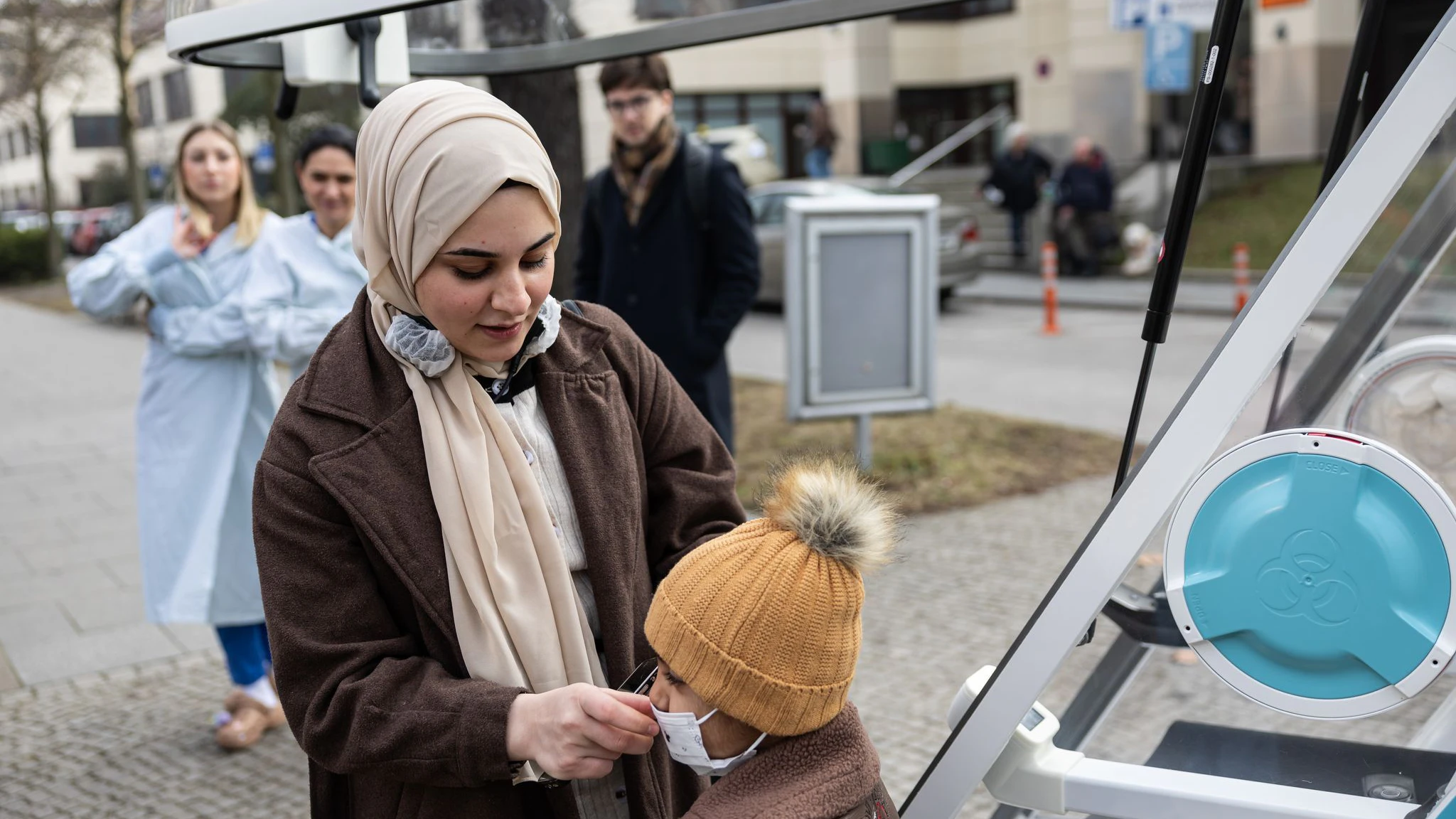 Batoul Kanjo, Ahmads Mutter, richtet die Maske ihres Sohnes bevor er in das Ein-Personen-Fahrzeug „Moby“ einsteigt.