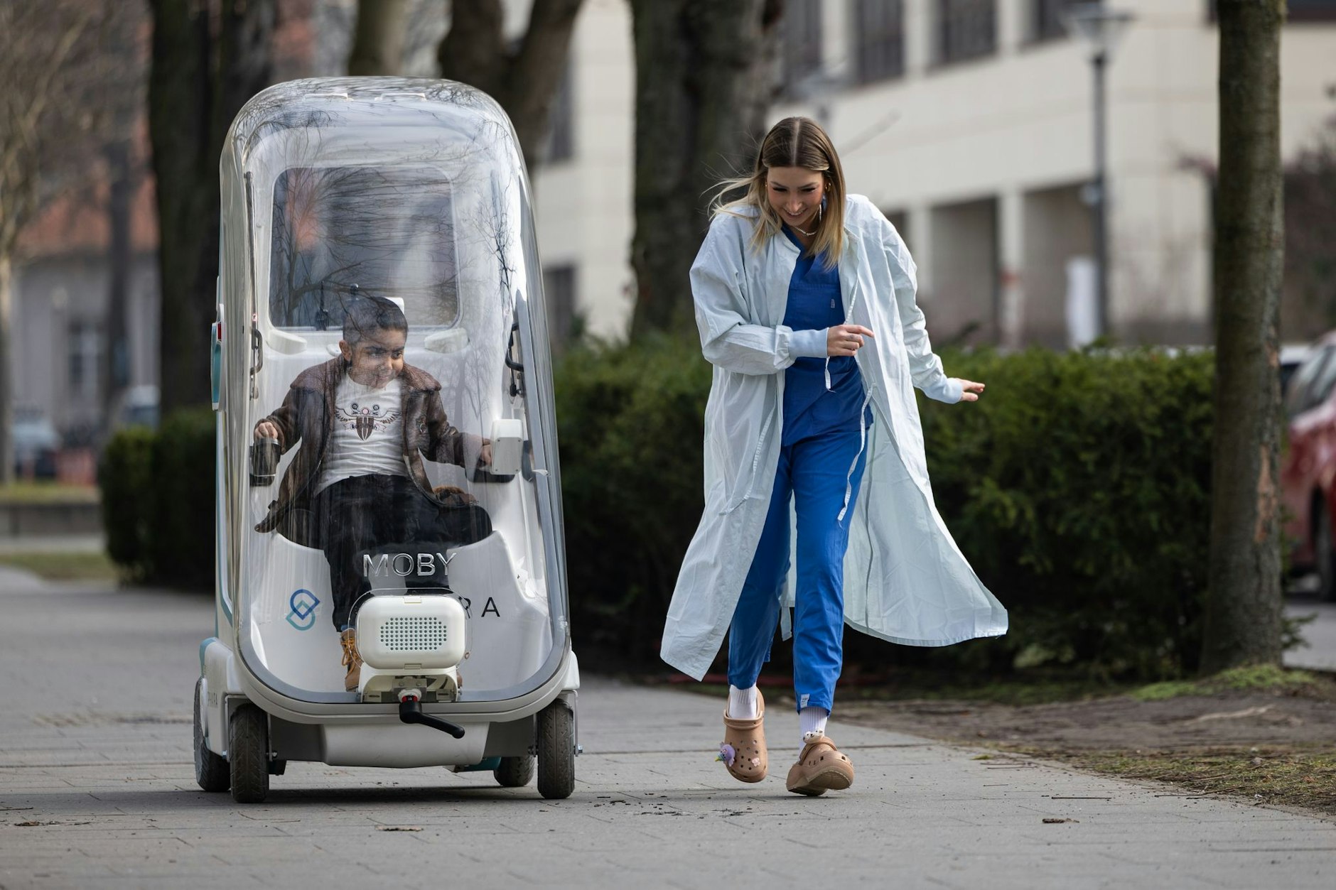 Ahmad steuert das Super-Mobil mit einem Joystick selber. Das Ein-Personen-Fahrzeug ist mit einer transparenten Haube und HEPA-Filtern ausgestattet und wurde von einem Startup in Berlin konzipiert. Es bietet Sicherheit und ermöglicht dennoch den direkten Austausch zwischen Patienten und ihren Angehörigen sowie dem Klinik- und Pflegepersonal.