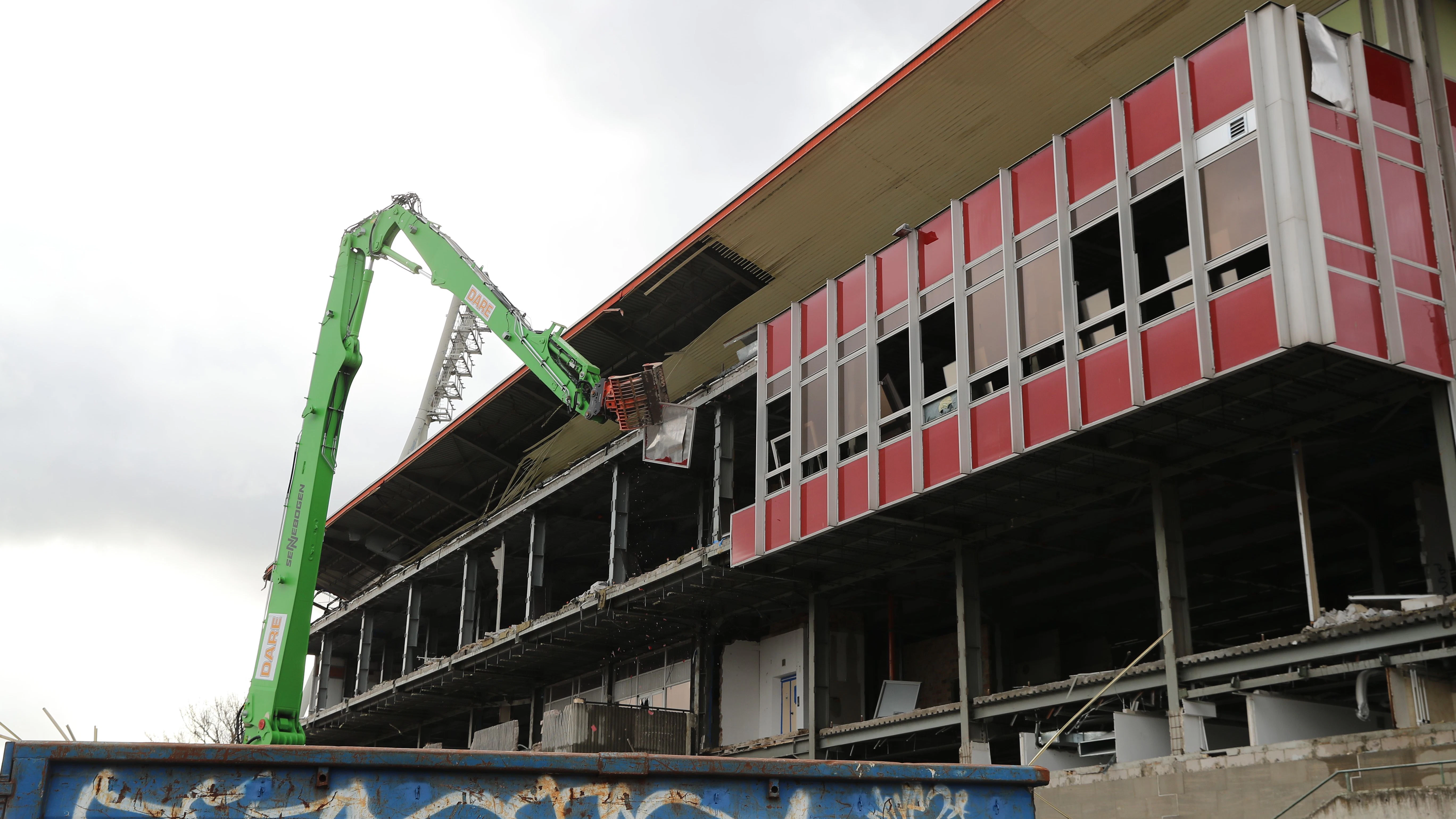 Die Glas-Beton-Fassade auf der Rückseite der Haupttribüne: Der Spezialbagger reist ein Teil nach dem anderen heraus ...