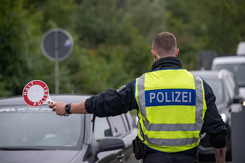 Ein Polizist hält Fahrzeuge an der Grenze zu Deutschland an.