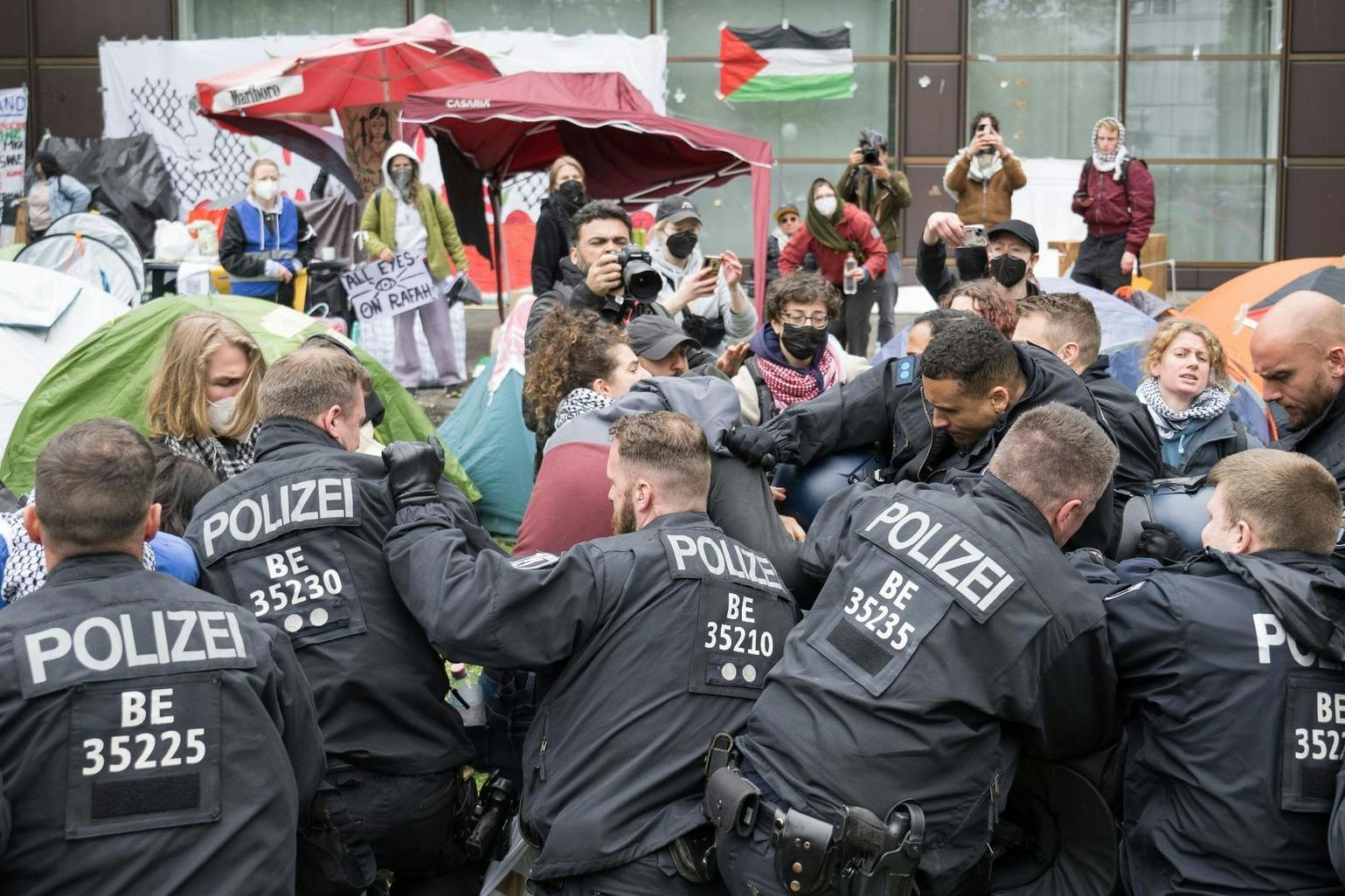 Polizeibeamte gehen während einer propalästinensischen Demonstration der Gruppe Student Coalition Berlin auf dem Theaterhof der Freien Universität Berlin gegen Demonstranten vor.