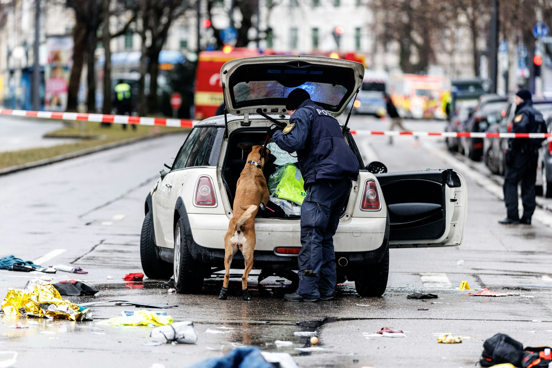 Polizisten untersuchen das Auto in der Nähe des Einsatzortes, mit dem ein Mann in die Menge gerast war: einen Mini.