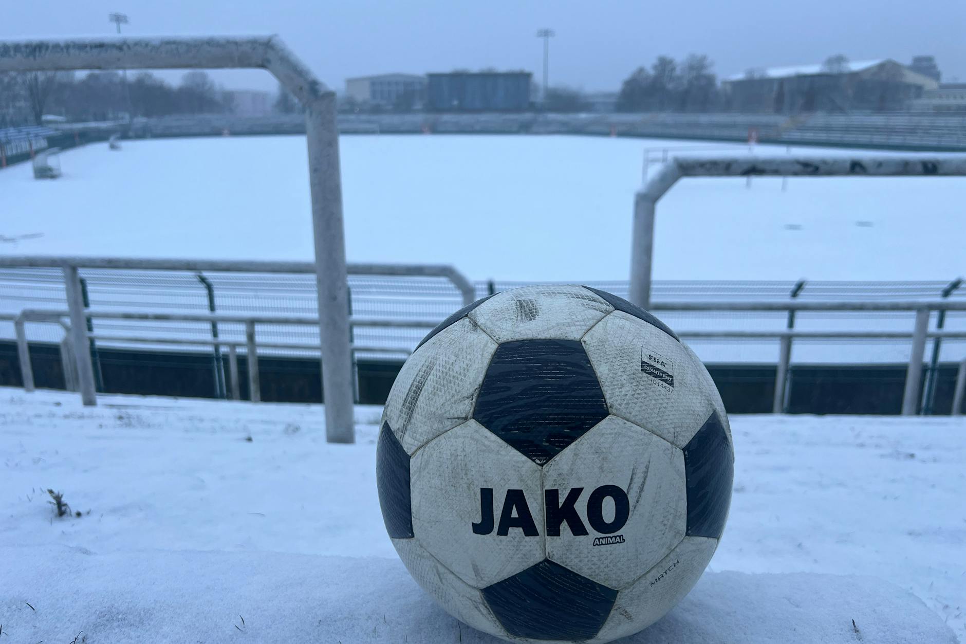 Spielabsage! Ein Fußball liegt allein auf den Traversen des eingeschneiten Sportforums.