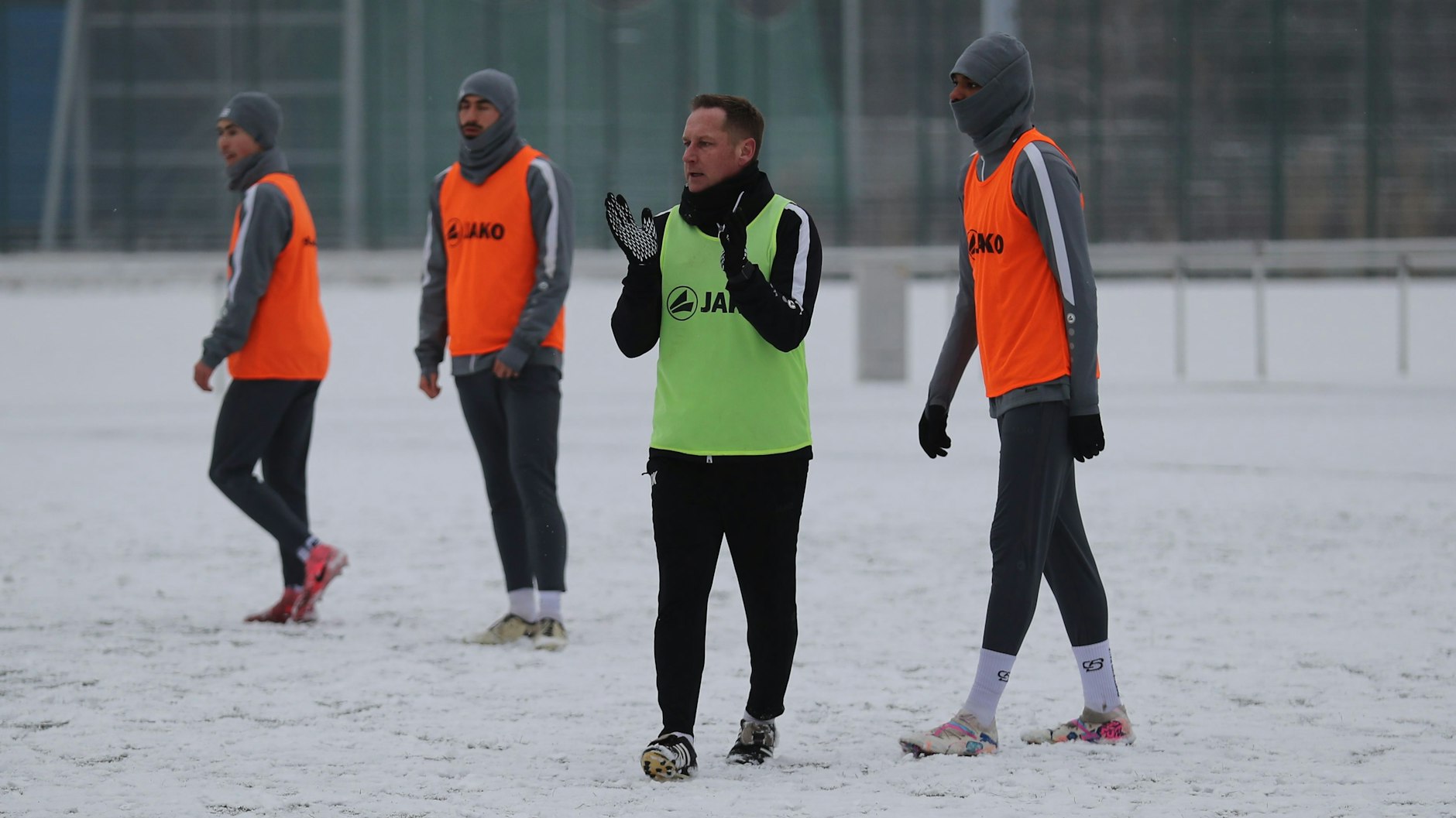 Trainer Dennis Kutrieb - ohne Mütze - treibt seine dick eingemummelten Spieler auf dem Kunstrasenplatz an.