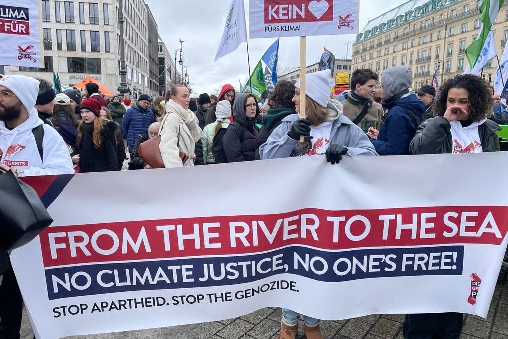 Mehrere Teilnehmer halten eine Plakat mit einer verbotenen Parole in die Höhe.