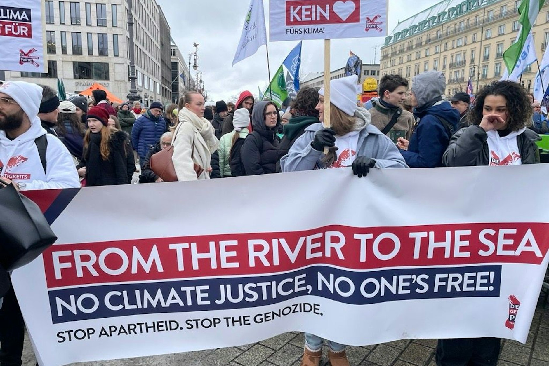 Mehrere Teilnehmer halten eine Plakat mit einer verbotenen Parole in die Höhe.