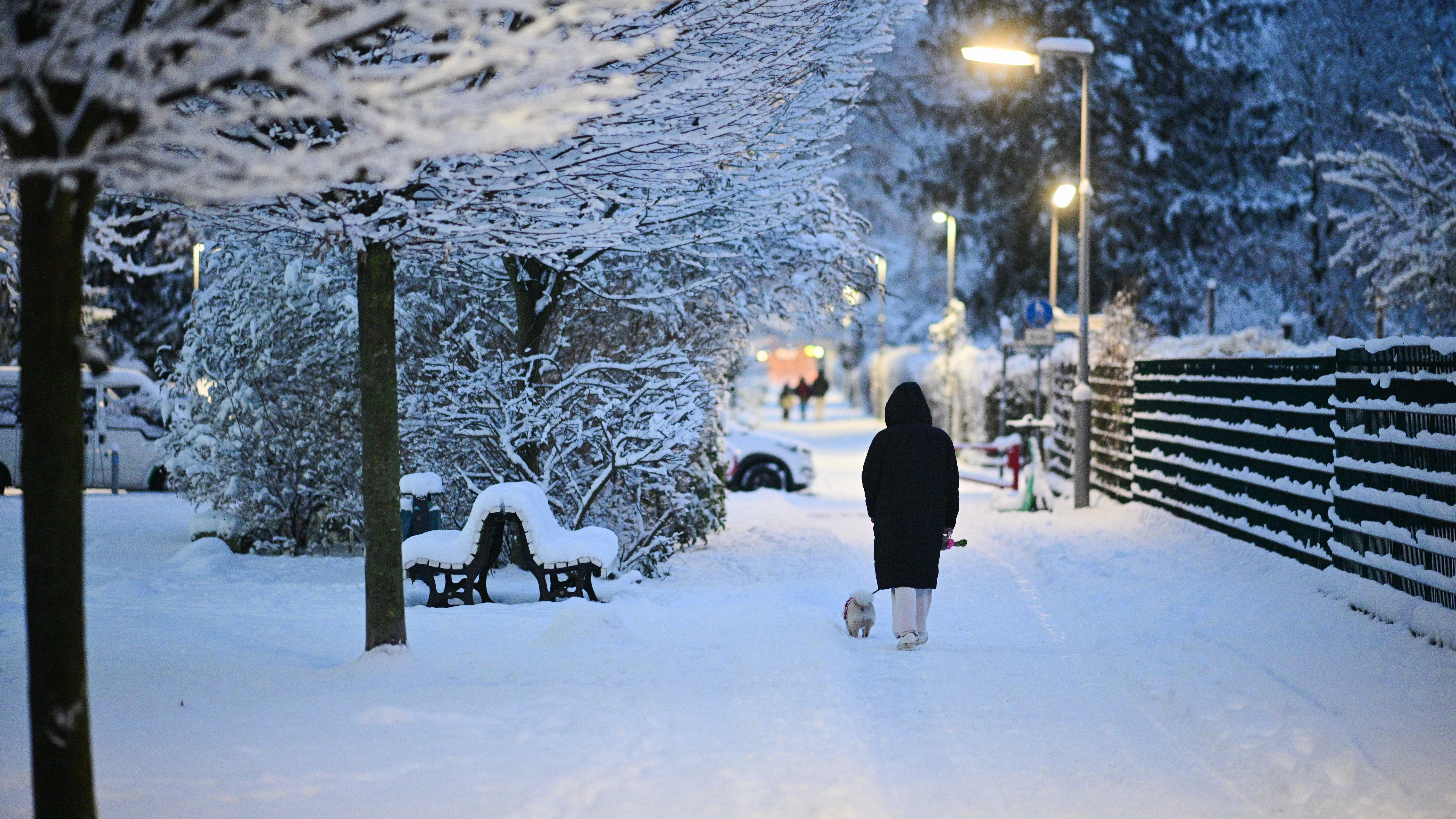Eine Frau geht durchs Winterwunderland. Berlin versinkt am Morgen im Schnee.