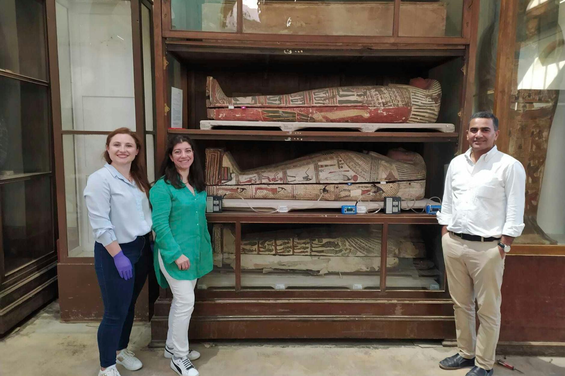 Von links: Emma Paolin, Doktorandin an der Universität von Ljubljana, Dr. Cecilia Bembibre, Dozentin am University College London, Prof. Dr. Abdelrazek Elnaggar, Mitglied des Forschungsteams am Ägyptischen Museum in Kairo, lächeln für ein Foto mit einer Auswahl der mumifizierten Körper.