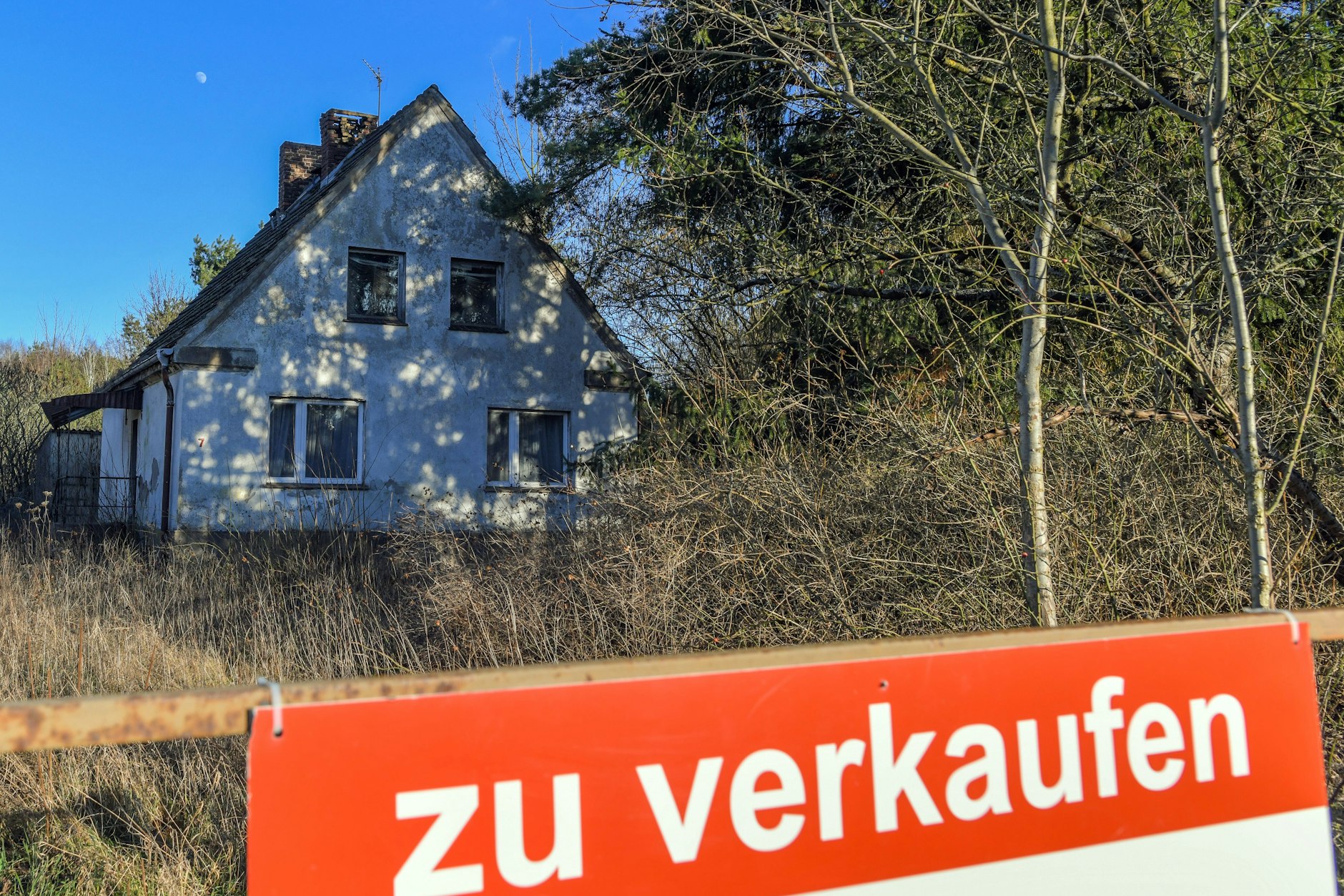 Ein Schild mit der Aufschrift «zu verkaufen» steht auf einem Grundstück mit einem Einfamilienhaus. (Archivfoto)