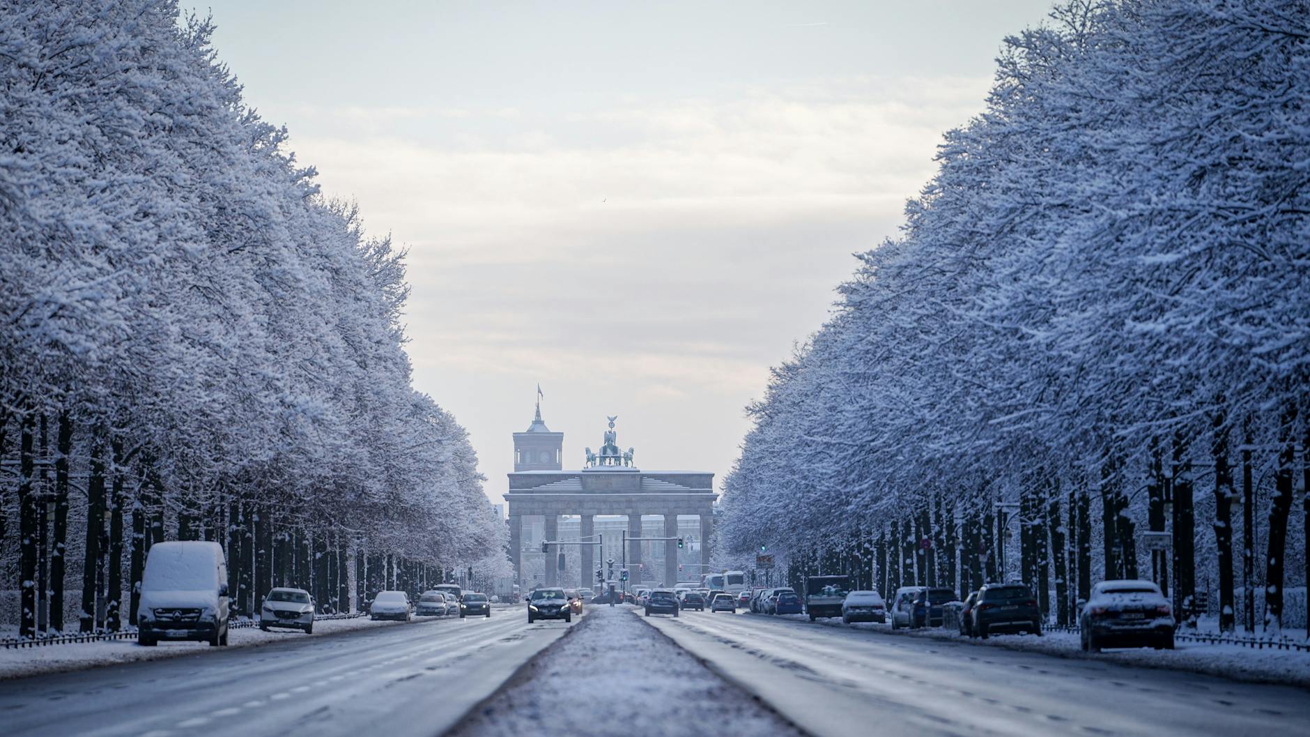 Schneebedeckte Bäume rahmen am Morgen das Brandenburger Tor ein.