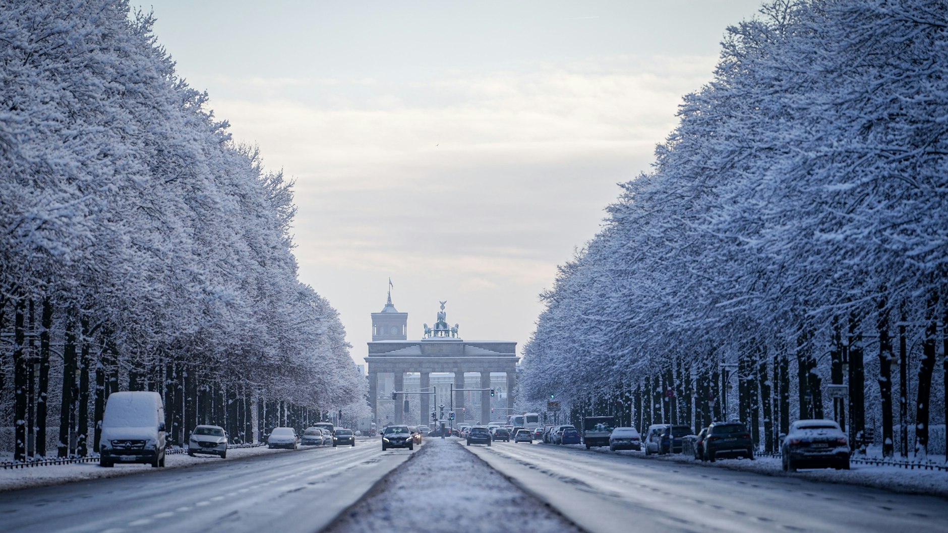 Schneebedeckte Bäume rahmen am Morgen das Brandenburger Tor ein.