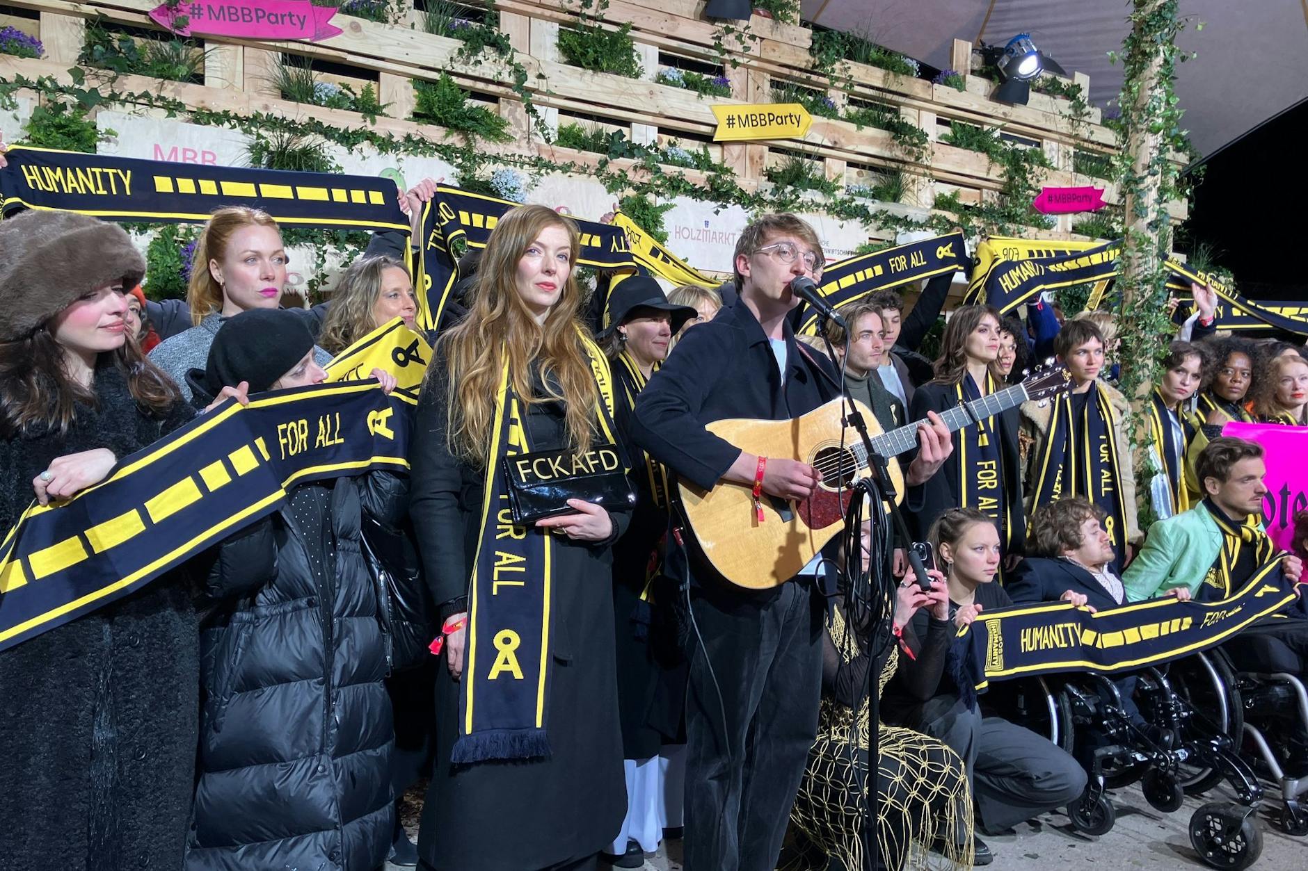 Singer-Songwriter Marlo Grosshardt (M.) mit Prominenten bei der Protestaktion von SOS Humanity während der diesjährigen Medienboard-Berlinale-Party.