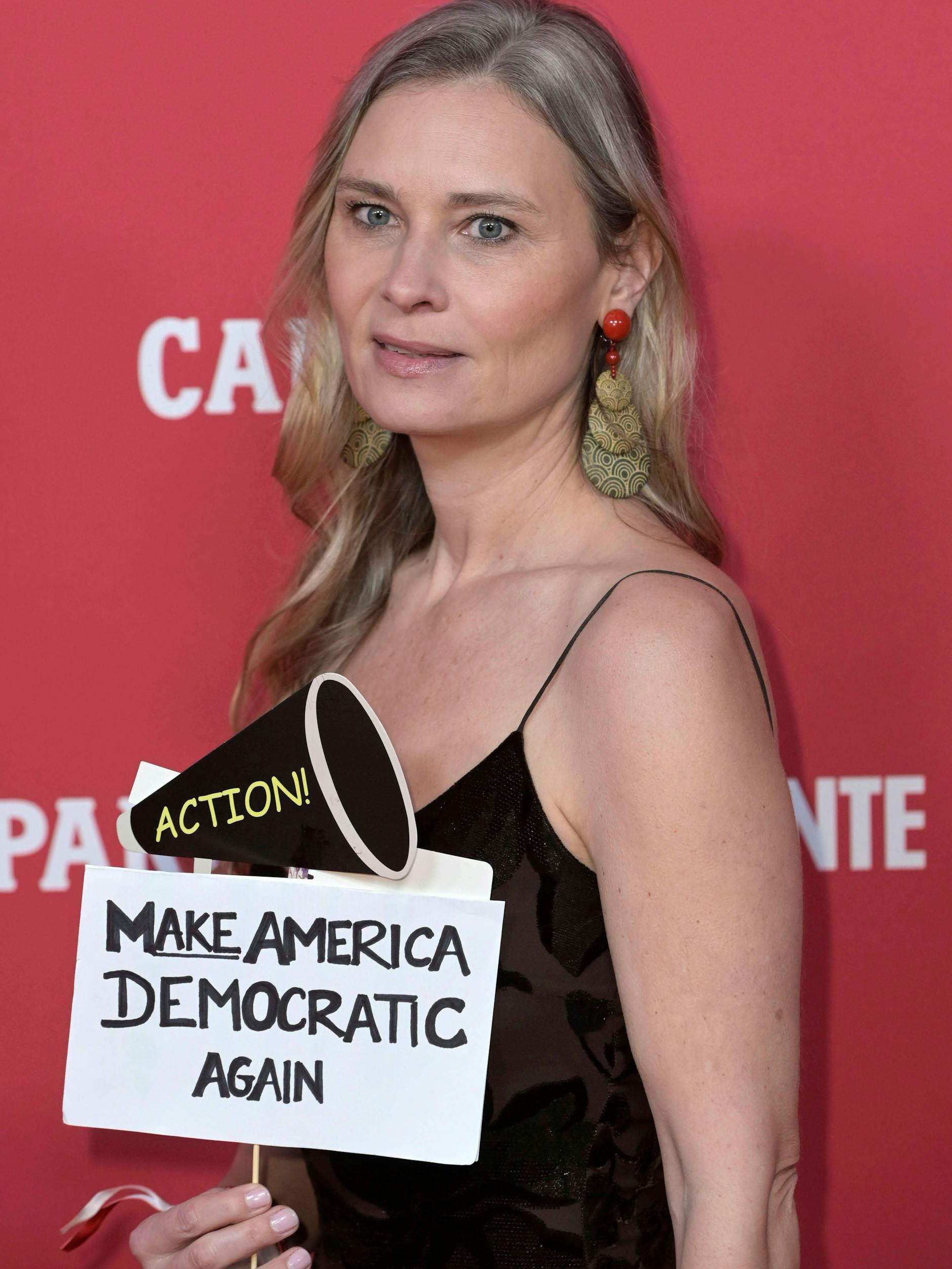 Die US-Schauspielerin Kristina Klebe wedelt auf der Campari-Berlinale-Party mit einem Pappschild herum, auf dem „Make America democratic again“ (Macht Amerika wieder demokratisch) steht.