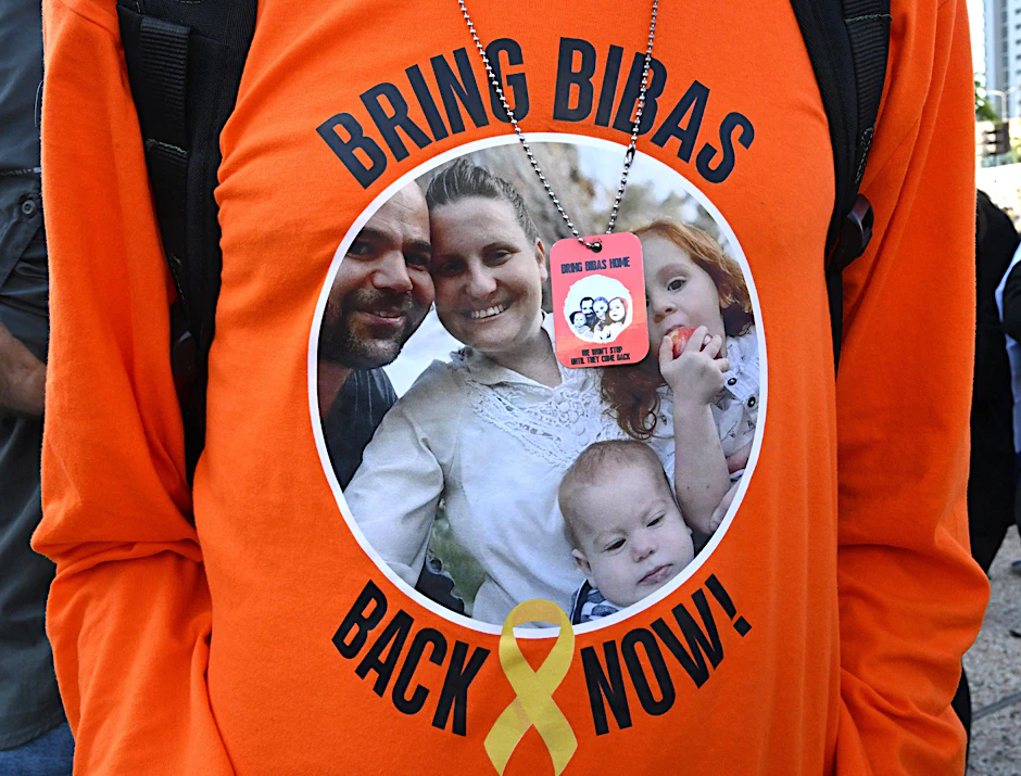 Ein Demonstrant trägt ein T-Shirt, auf dem die Familie Bibas abgebildet ist.