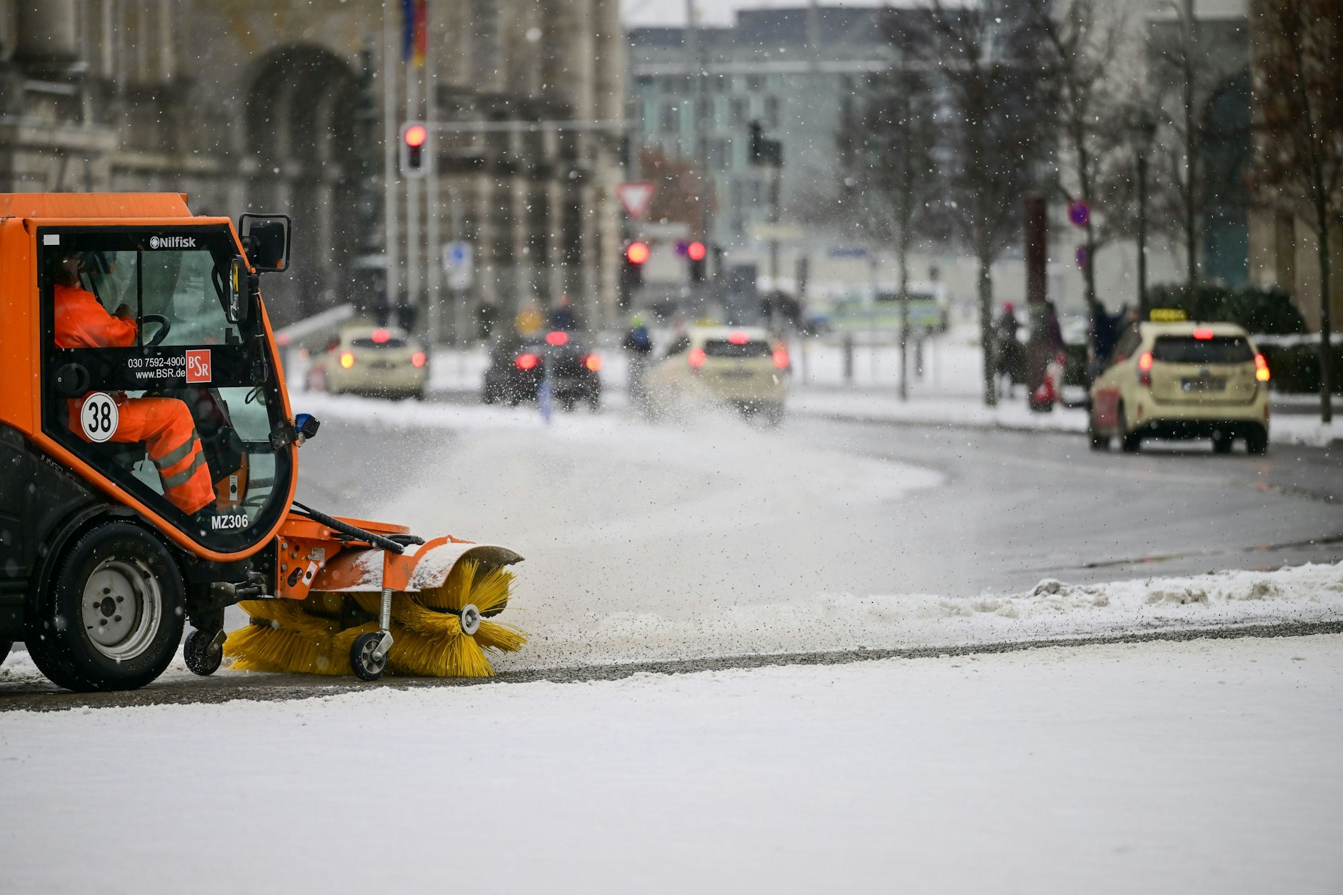 Ein Fahrzeug der Berliner Stadtreinigung (BSR) kehrt in der Innenstadt Schnee von einem Radweg.