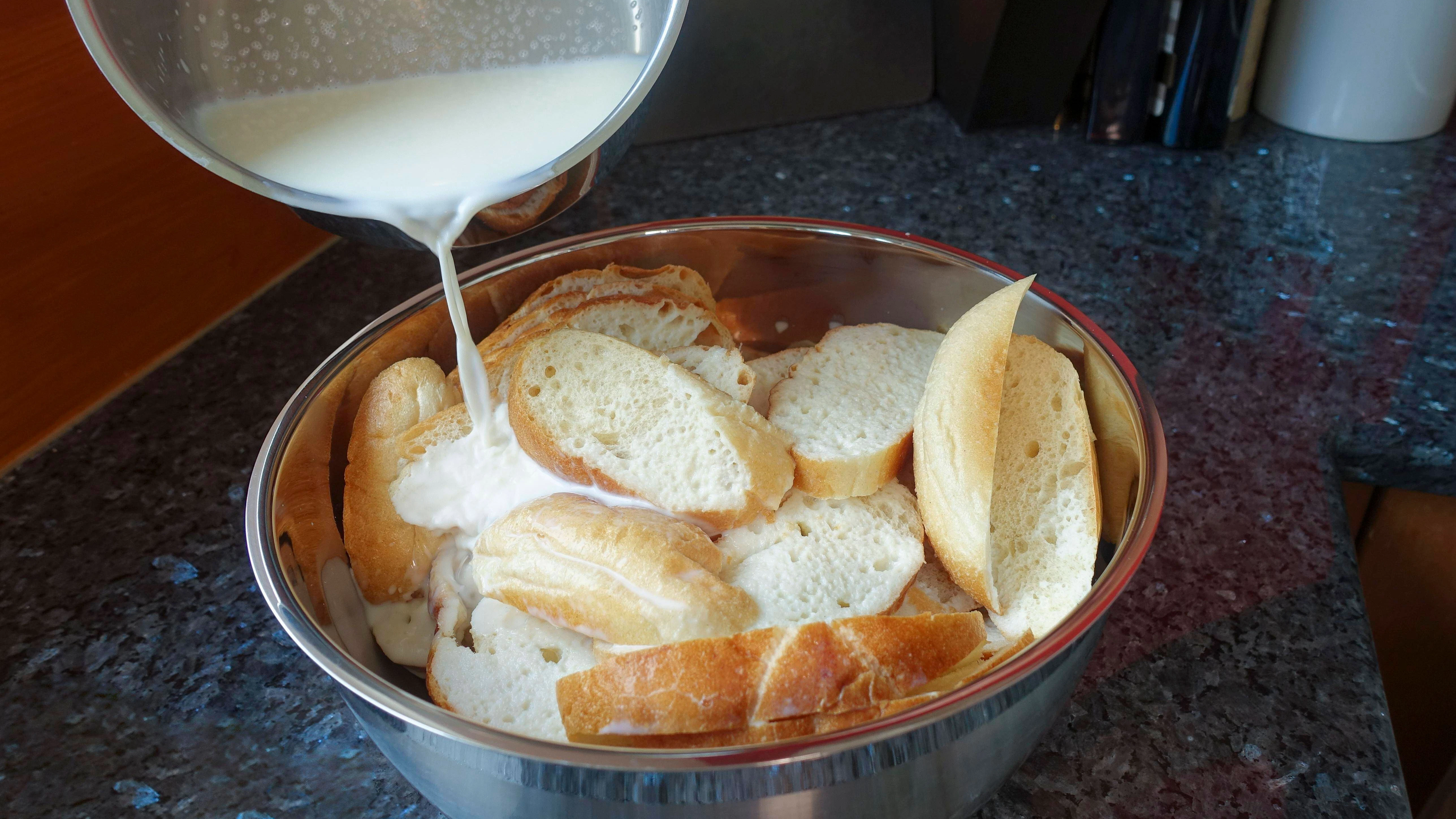 Die geschnittenen Brötchen werden in der warmen Milch eingeweicht.
