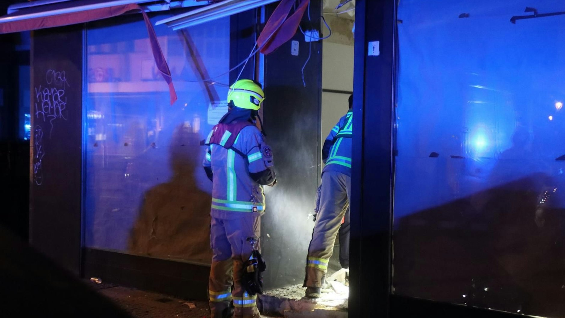 Einsatzkräfte der Feuerwehr untersuchen das Ladengeschäft in Neukölln, von dem die Explosion ausging.
