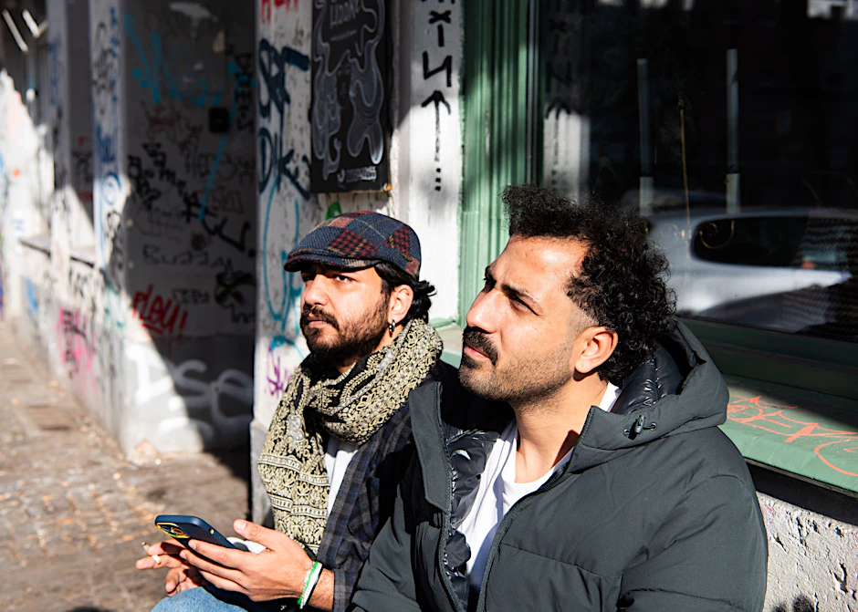 Vor dem kleinen Friseursalon Studio 14 in der Neuköllner Hobrechtstraße sitzt Betreiber Shadi (r.) mit seinem Freund Khaled.