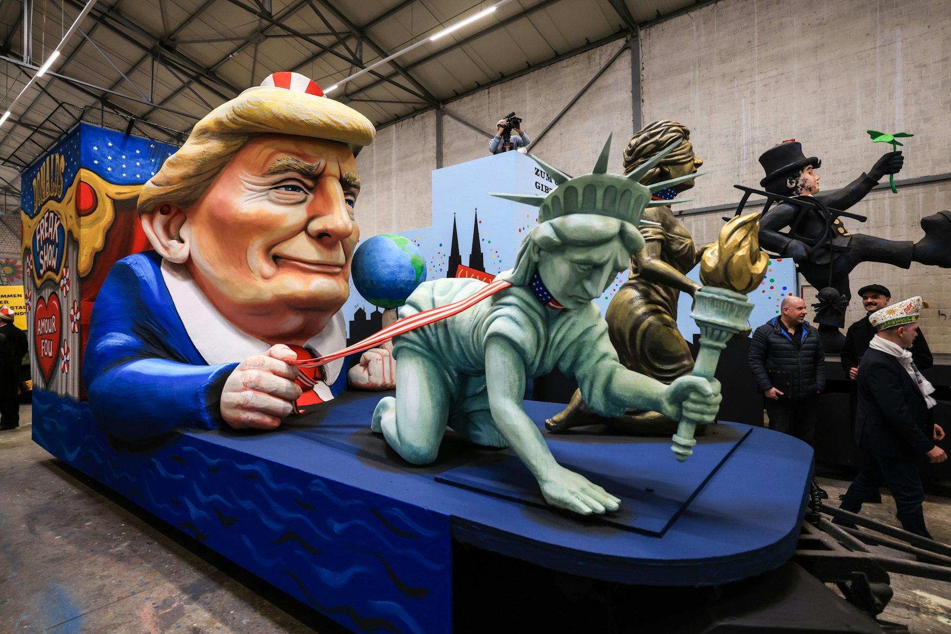 Freiheit und Recht werden von Donald Trump als Zirkusdirektor an der Leine geführt. Ein Motivwagen zum Thema Trump steht beim Richtfest des Kölner Rosenmontagszuges in der Wagenhalle.