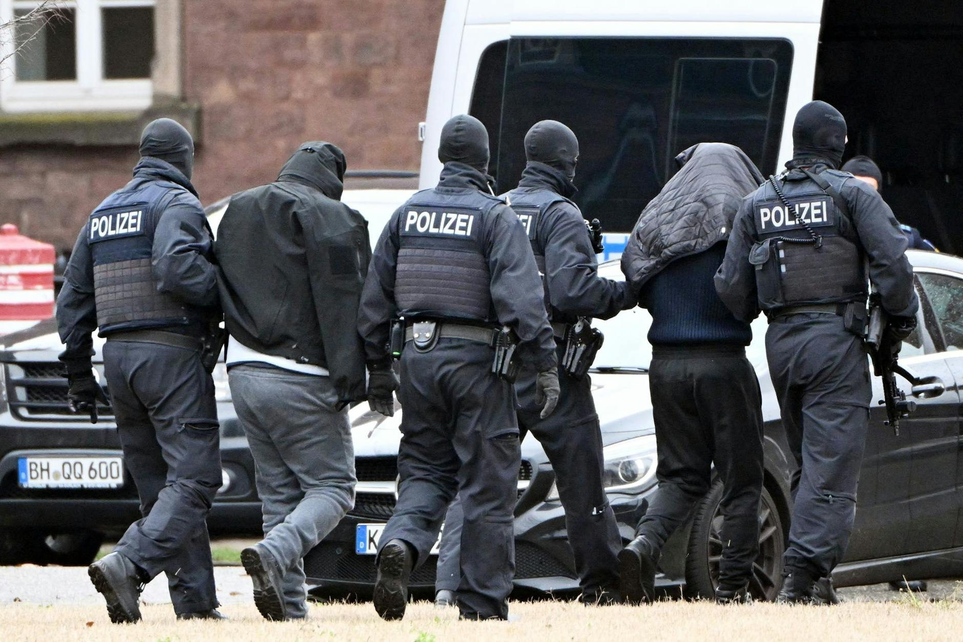 Zwei mutmaßliche Hamas-Mitglieder werden von Polizisten von einem Hubschrauber zu einem Auto geführt.