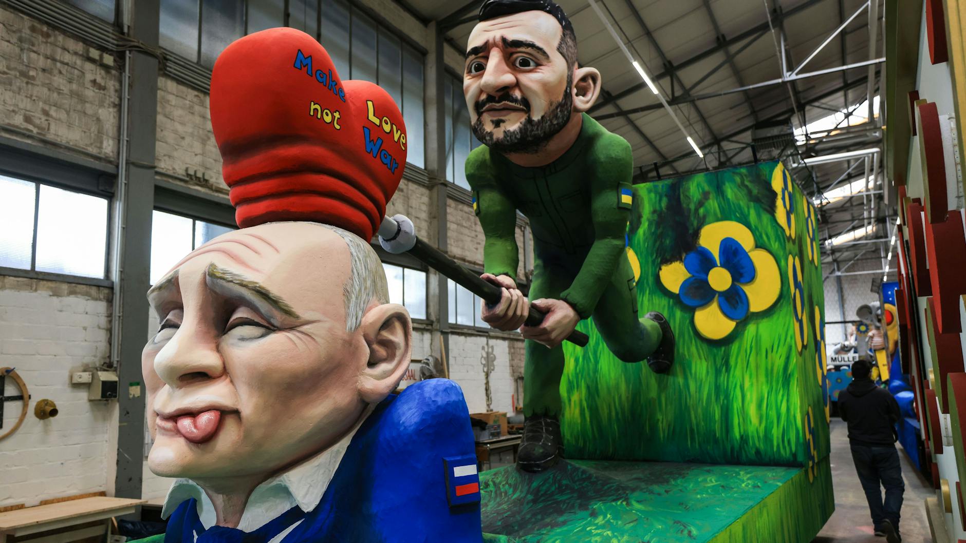 Der ukrainische Präsident Wolodymyr Selenskyj versucht dem russischen Präsidenten Wladimir Putin die Botschaft „Make Love not War“ einzuhämmern. Motivwagen des Kölner Rosenmontagszuges