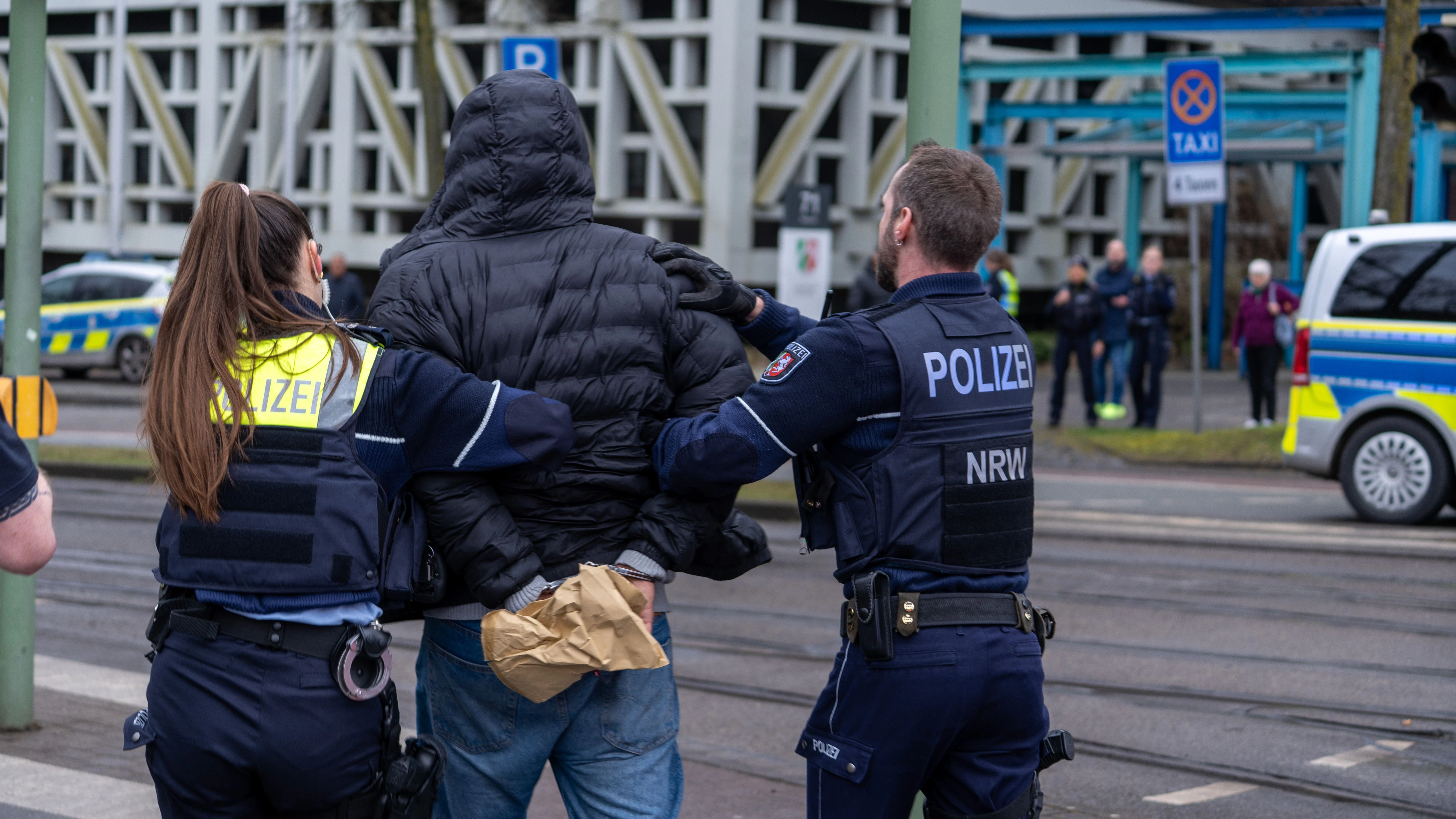 Bielefeld: Einsatzkräfte der Polizei führen einen Mann in der Nähe von einem Tatort in Handschellen ab.