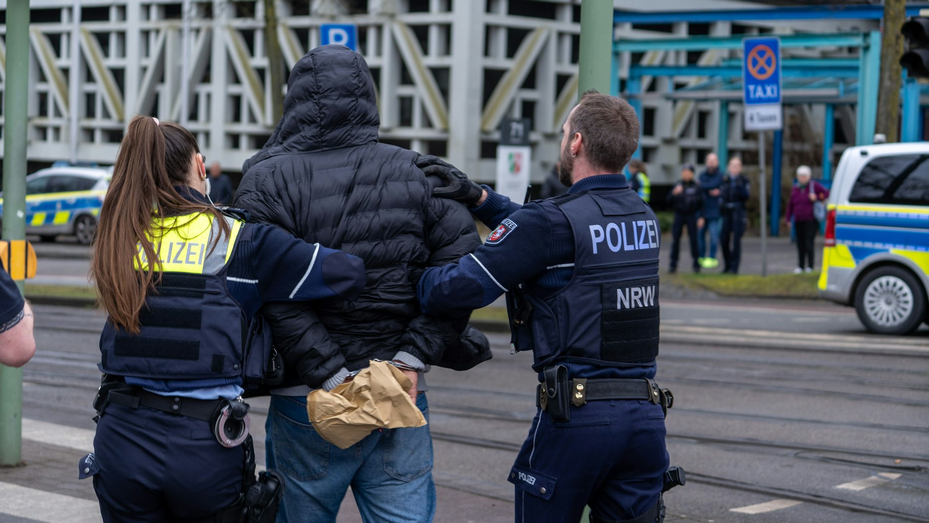 Bielefeld: Einsatzkräfte der Polizei führen einen Mann in der Nähe von einem Tatort in Handschellen ab.