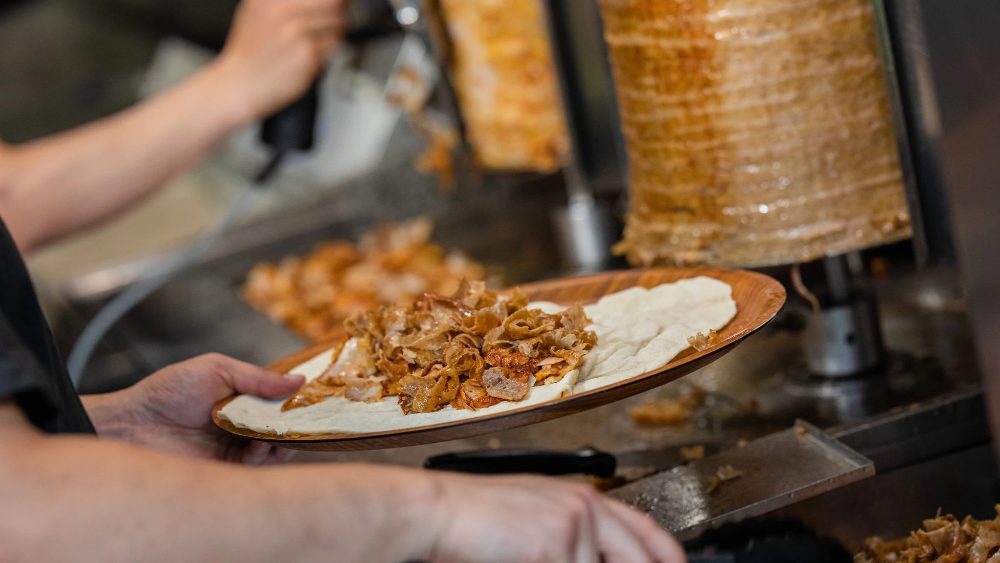 Ein Mitarbeiter einer Dönerbude legt Fleisch auf einen Döner. Bald werden die Preise für Döner noch mehr explodieren. 