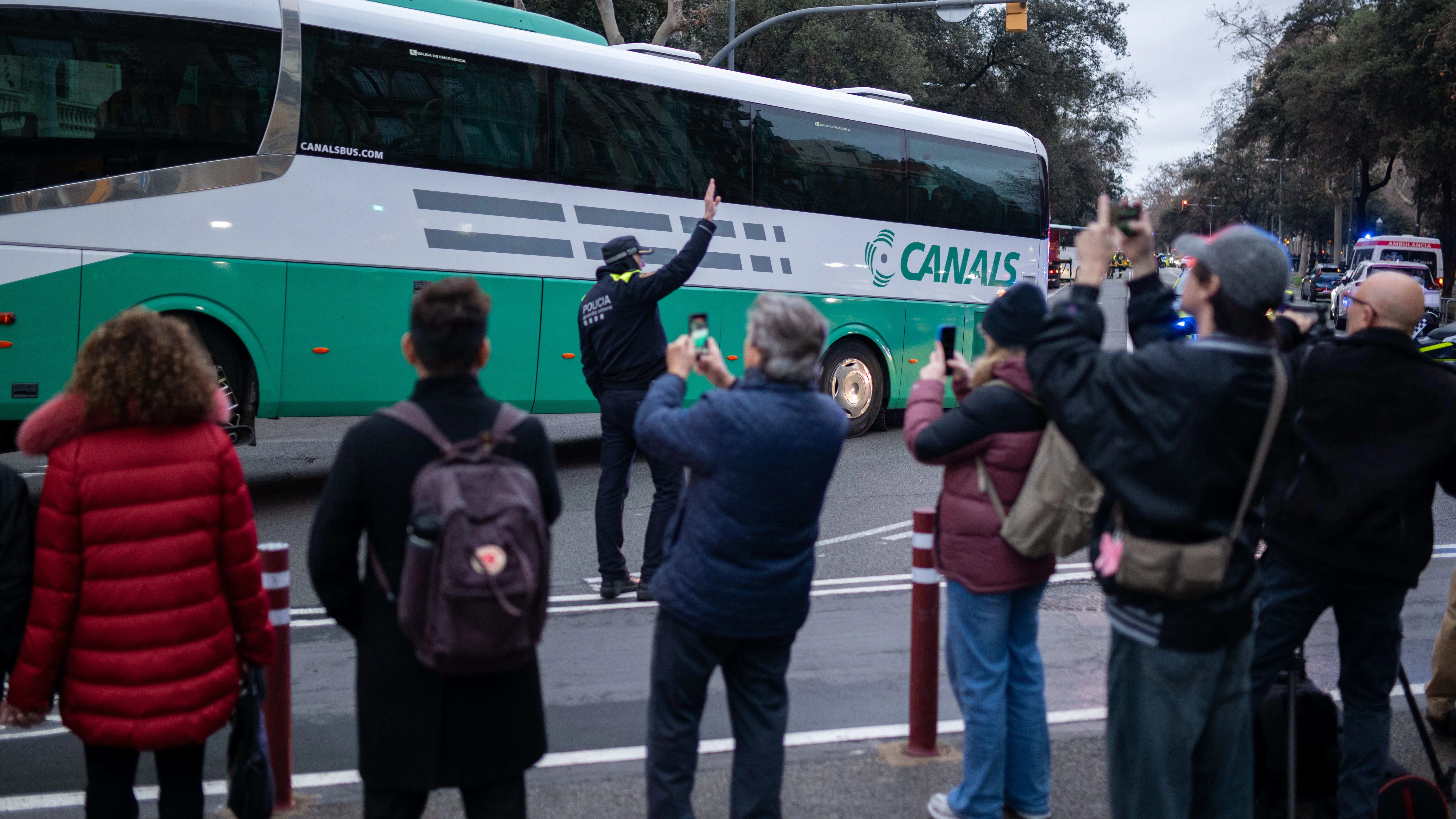 Menschen fotografieren mit ihren Handys, während mehrere Rettungsdienste nach dem Zusammenstoß von zwei Bussen in Barcelona im Einsatz sind.