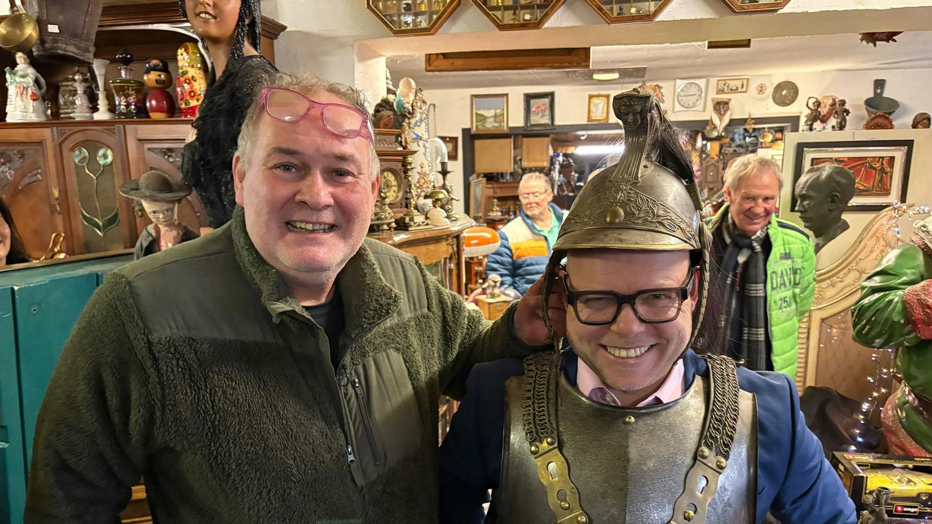 Walter Lehnertz und sein Händlerkollege Leo Leo mit antikem Helm im Geschäft in der Eifel.