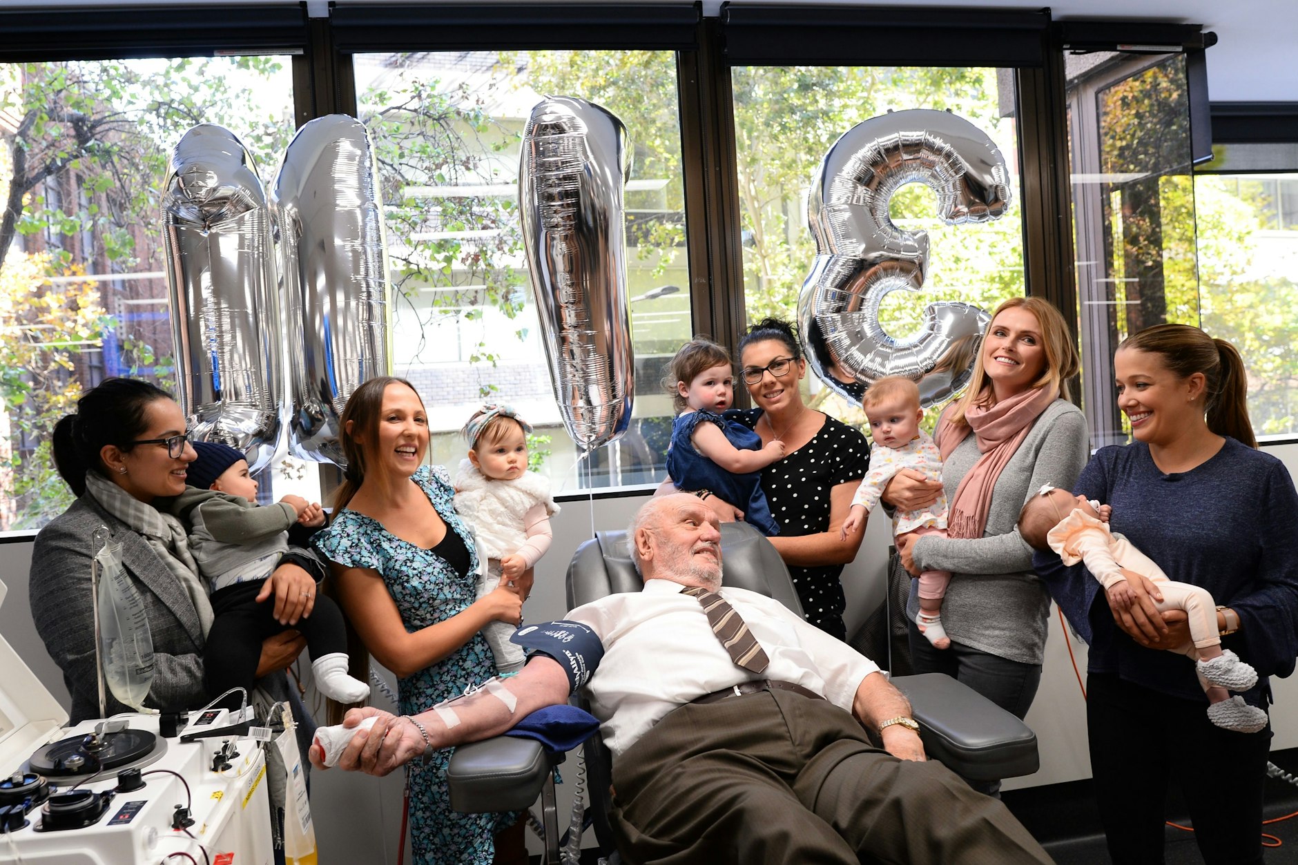 James Harrison bei seiner letzten Blutspende im Jahr 2018, umringt mit Babys und Mütter, deren Leben er rettete.