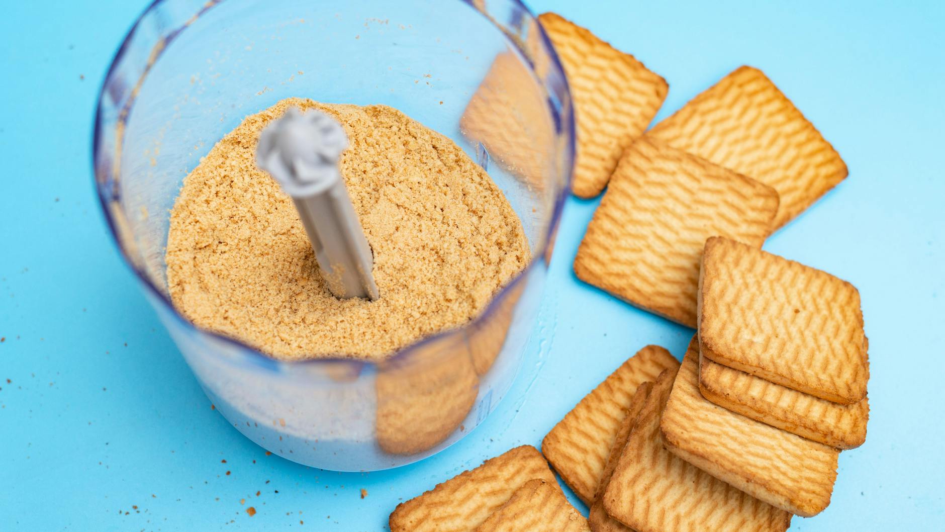 Im Mixer werden aus den Keksen ganz schnell die Brösel für den Kuchenboden. Mit dem Nudelholz klappt das auch gut.