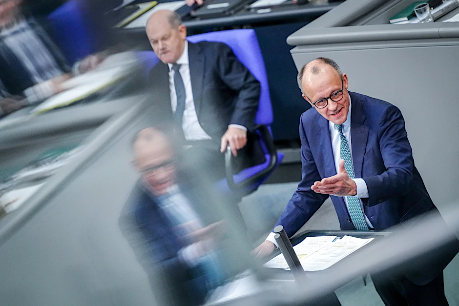 Friedrich Merz (r), CDU-Bundesvorsitzender, spricht im Bundestag neben Kanzler Olaf Scholz (SPD).