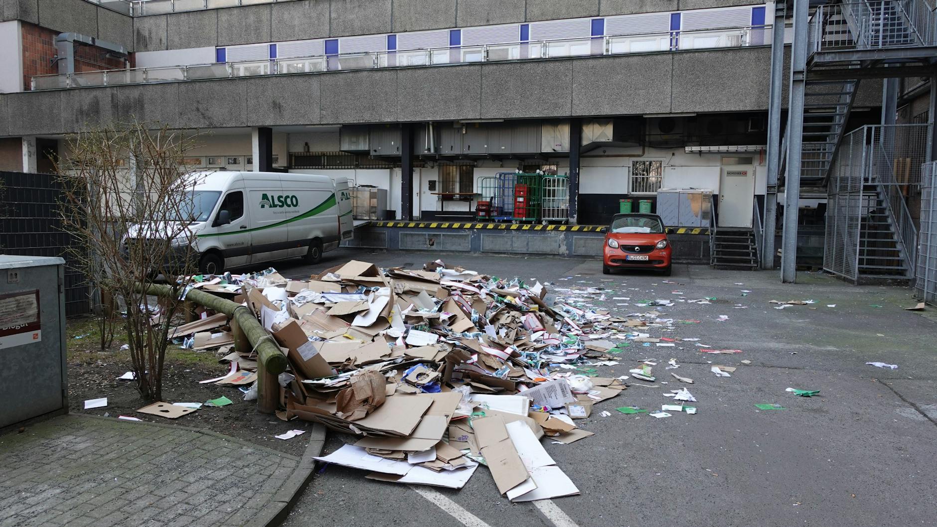 In diesem Wirtschaftshof in der Rosenstraße in Berlin-Mitte passierte das Unglück: Das Altpapier aus dem Container, in dem der Mann schlief, liegt jetzt auf dem Asphalt zerstreut.