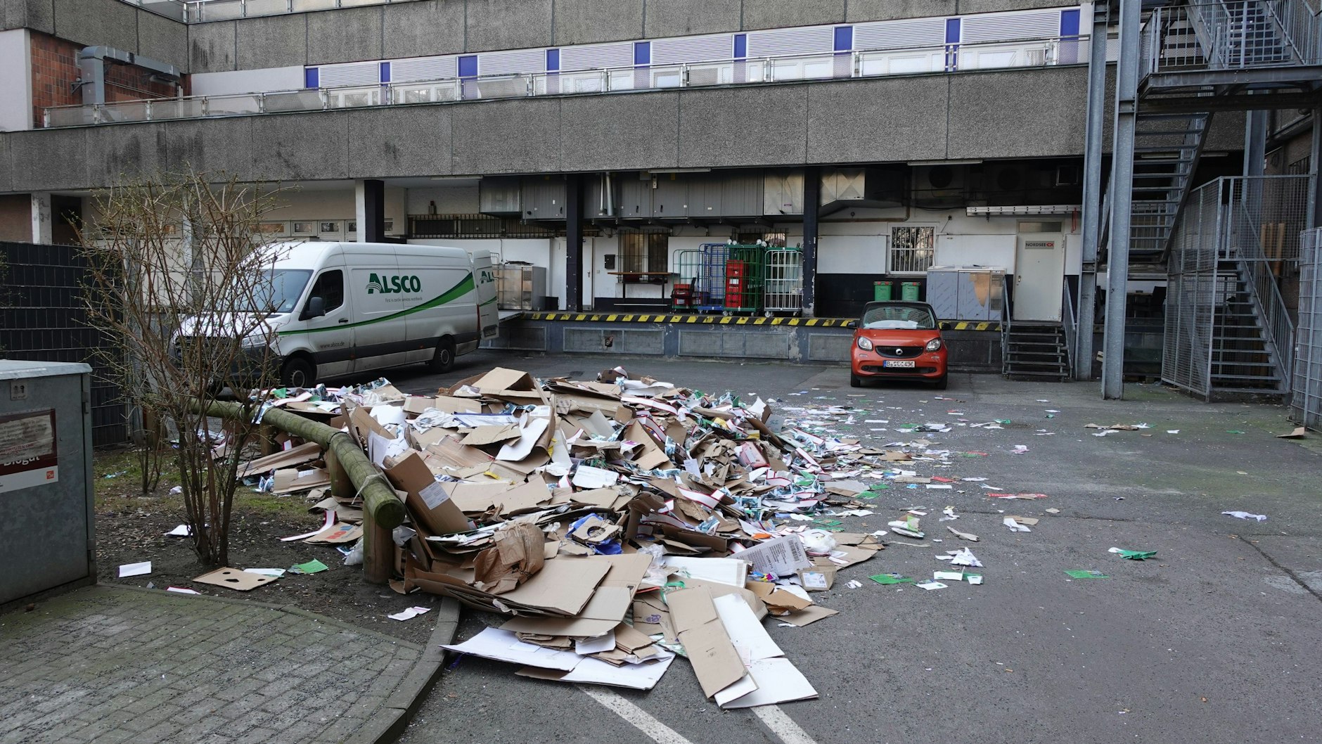 In diesem Wirtschaftshof in der Rosenstraße in Berlin-Mitte passierte das Unglück: Das Altpapier aus dem Container, in dem der Mann schlief, liegt jetzt auf dem Asphalt zerstreut.