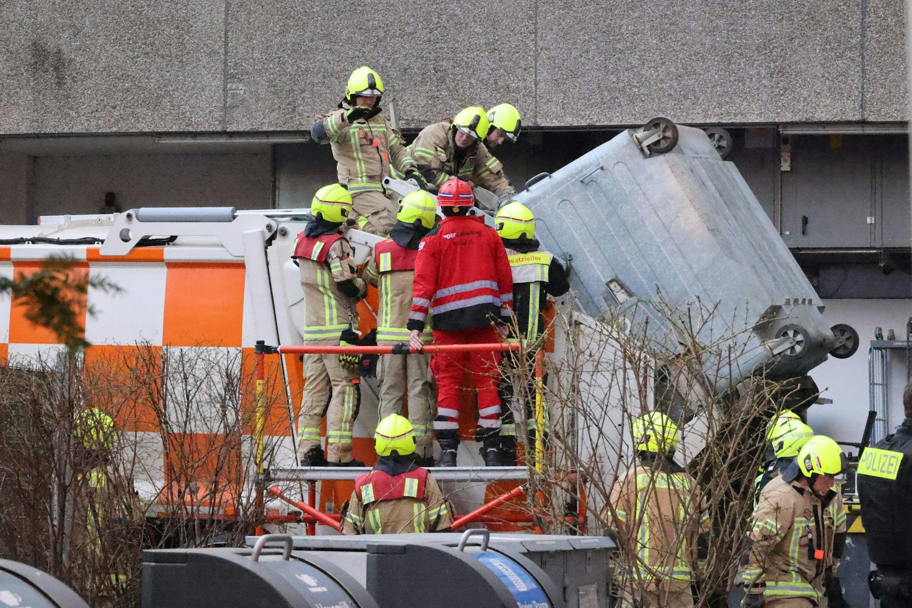 Das Todesdrama in der Rosenstraße in Berlin-Mitte: Der Container hängt noch an dem Müllwagen. Feuerwehrleute versuchen, den Obdachlosen zu befreien.
