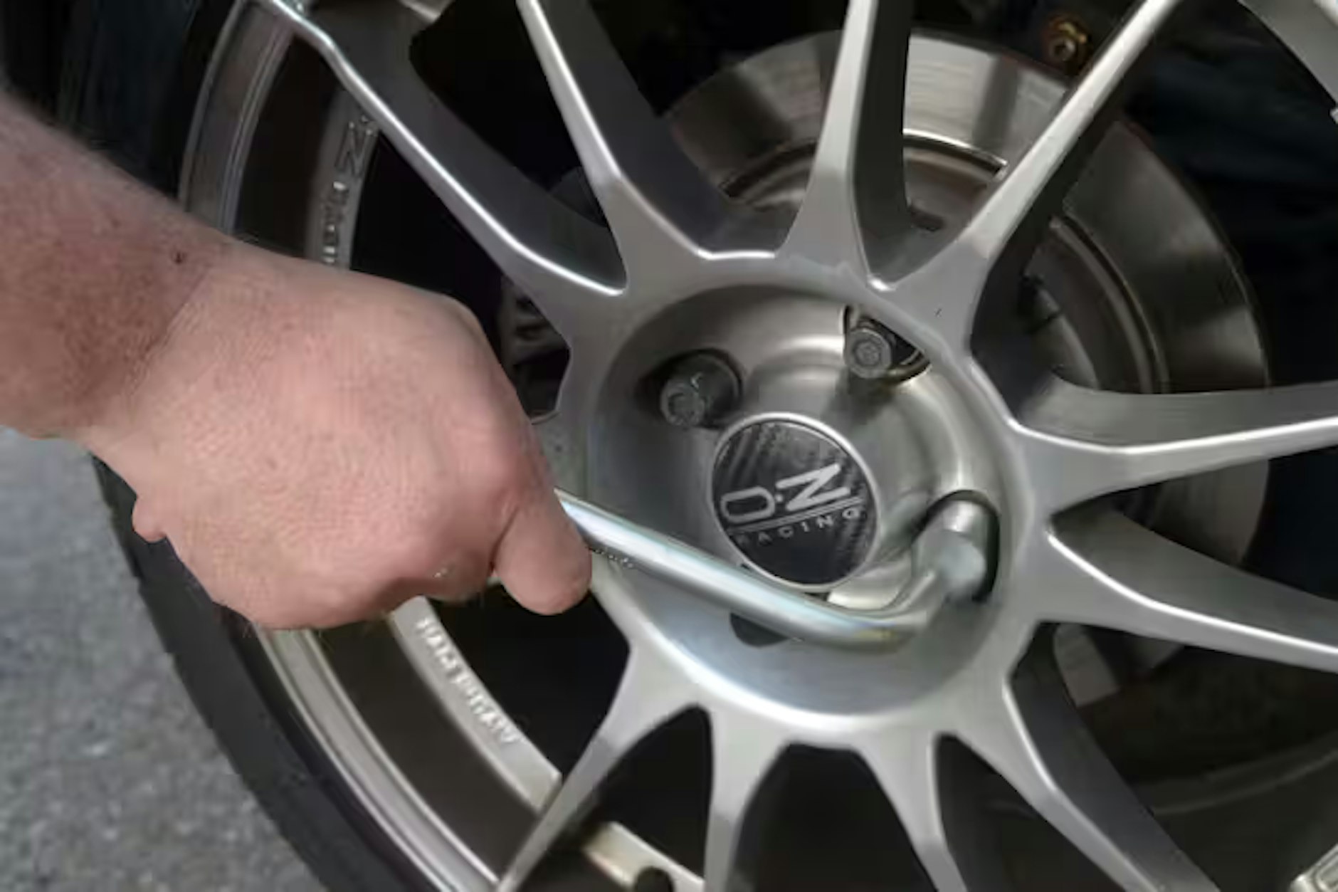 Ein Mann zieht eine Radmutter an einer Autofelge nach