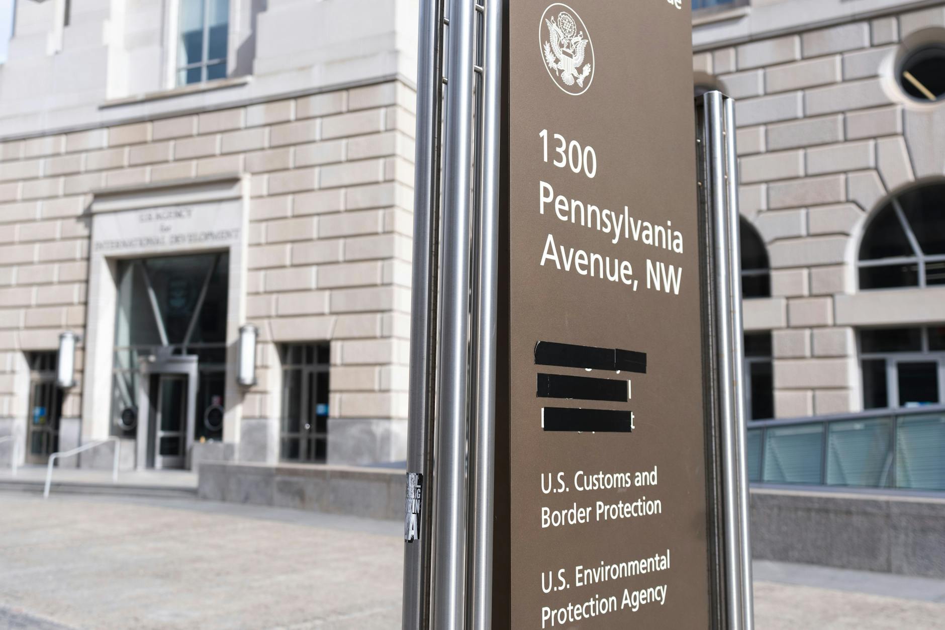 Ein Straßenschild mit den Namen der US-Regierungsbehörden, die im Ronald Reagan Building untergebracht sind. Die United States Agency for International Development (USAID) wurde weggetaped.
