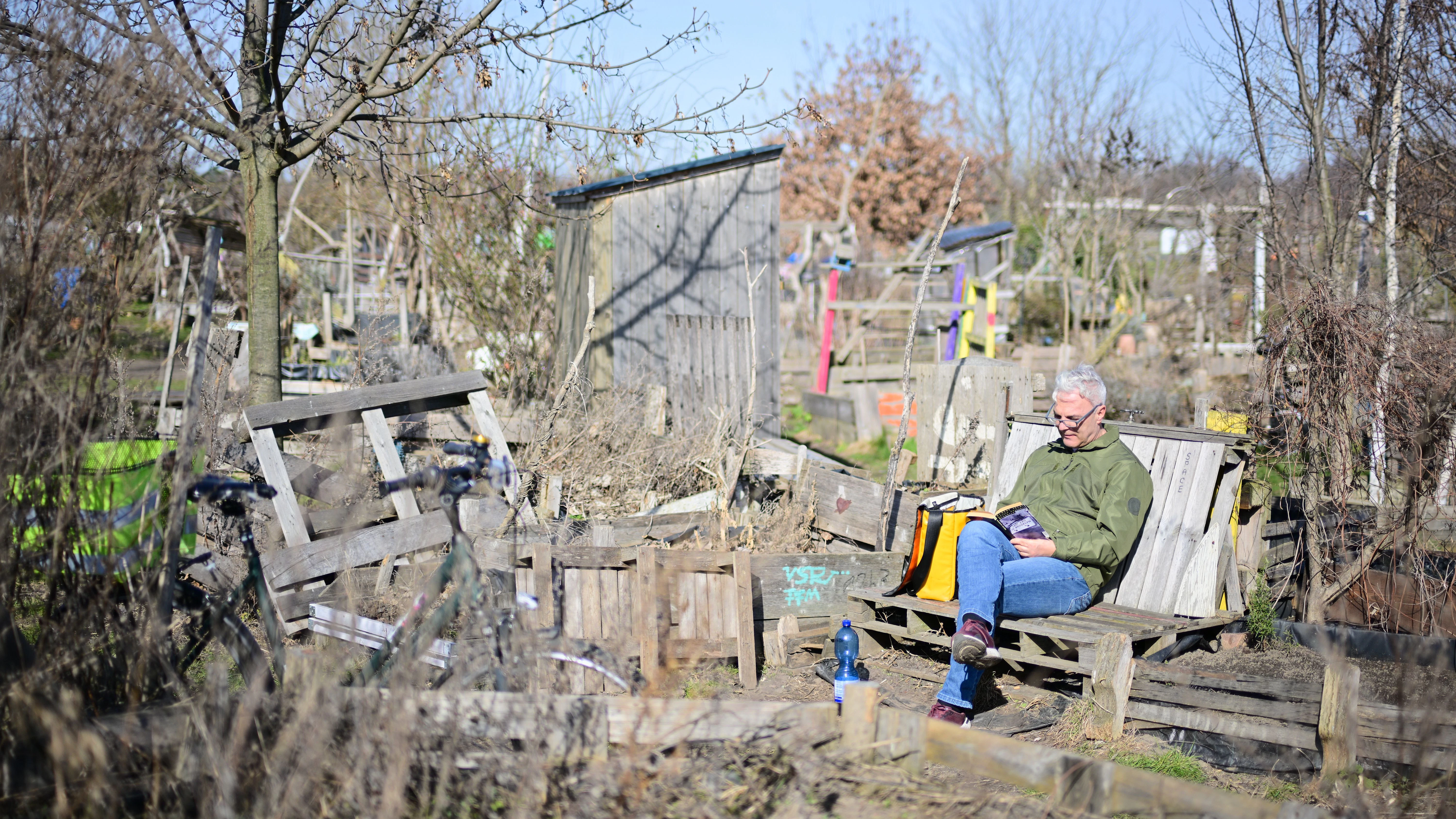 Peter sitzt auf einer Bank in den Gemeinschaftsgärten auf dem Tempelhofer Feld in der Sonne.