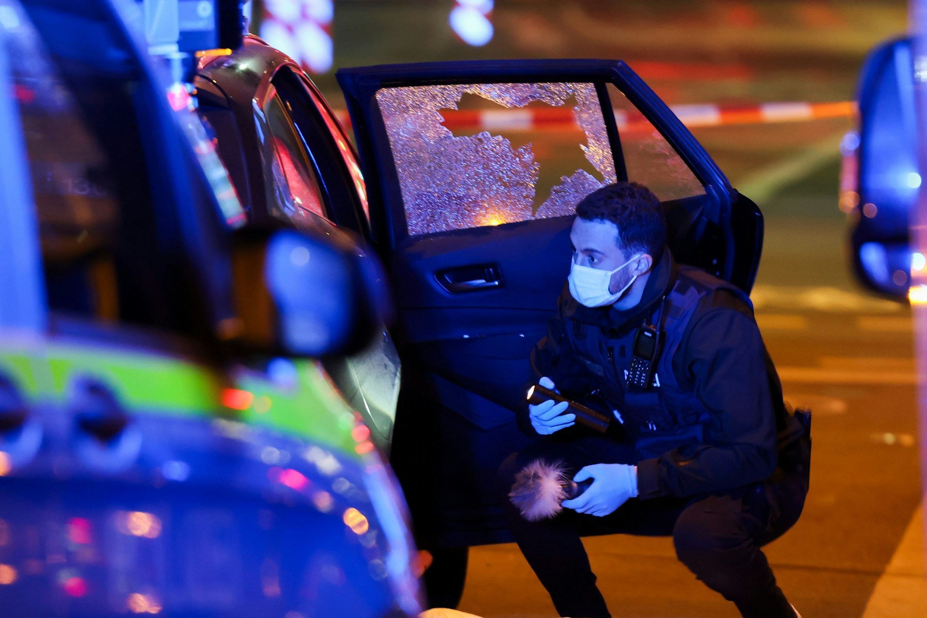 Ein Beamter der Polizei untersucht einen Tatort. In der Düsseldorfer Innenstadt wurde ein Mann in seinem Auto erschossen.