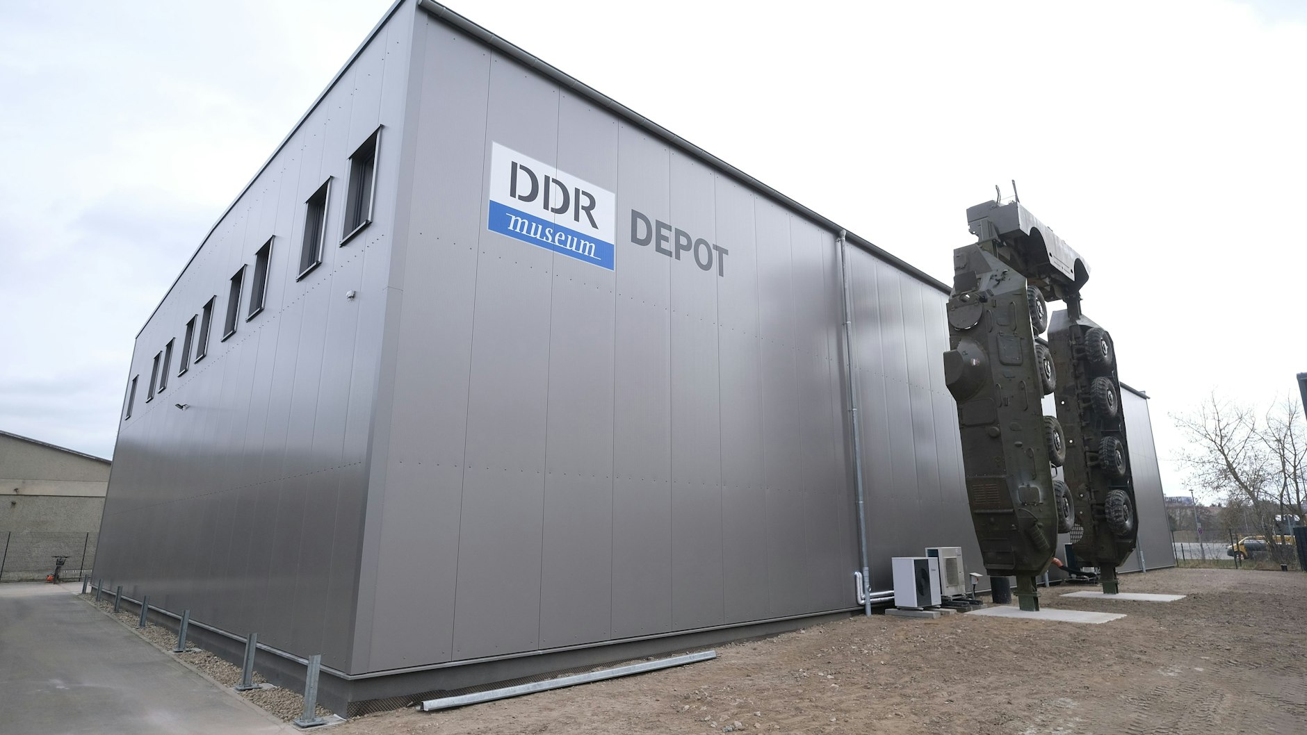 Vor der neu gebauten Halle in Marzahn steht ein zerlegter Panzer. Auch große Teile der Berliner Mauer sind zu sehen.