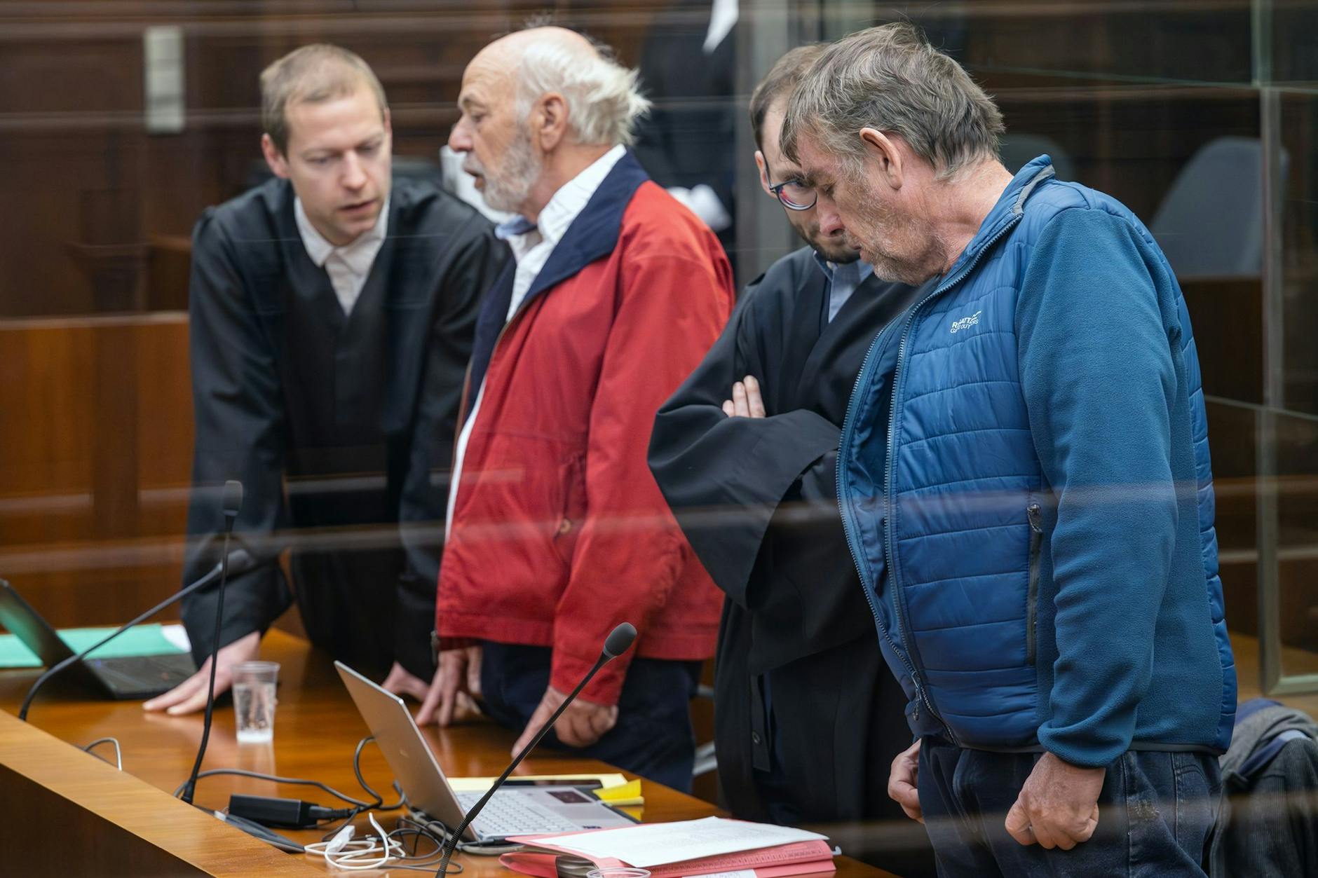 Die Angeklagten Peter K. (2.v.l.) und Thomas W. (r.) stehen vor dem Prozessbeginn in einem Saal des Berliner Kammergerichts mit ihren Verteidigern Lukas Theune (l.) und Benjamin Derin (2.v.r., verdeckt).