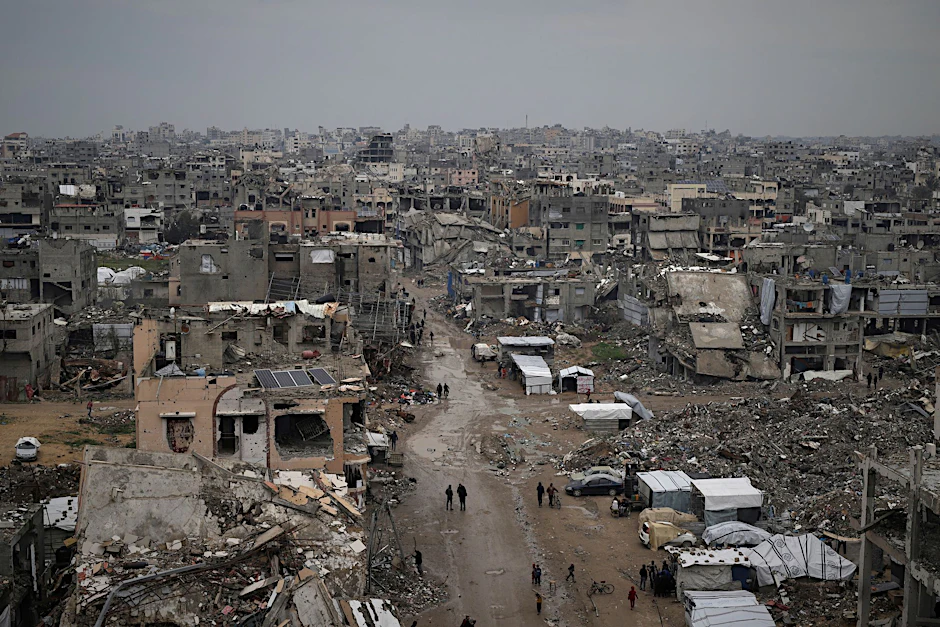 Palästinenser gehen durch die Trümmer zerstörter Häuser und Gebäude in Gaza-Stadt.