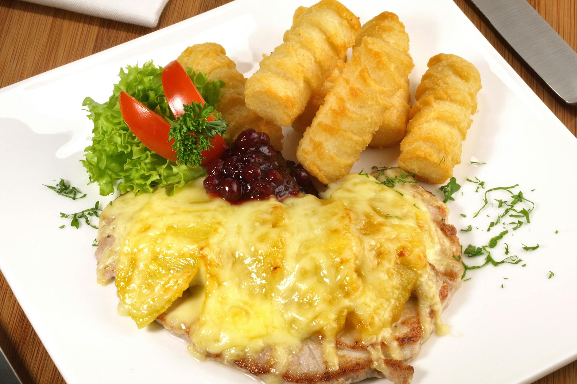 Steak Hawaii: Die Schweinesteaks werden mit Ananas belegt und mit Käse überbacken. Dazu passen Kroketten.