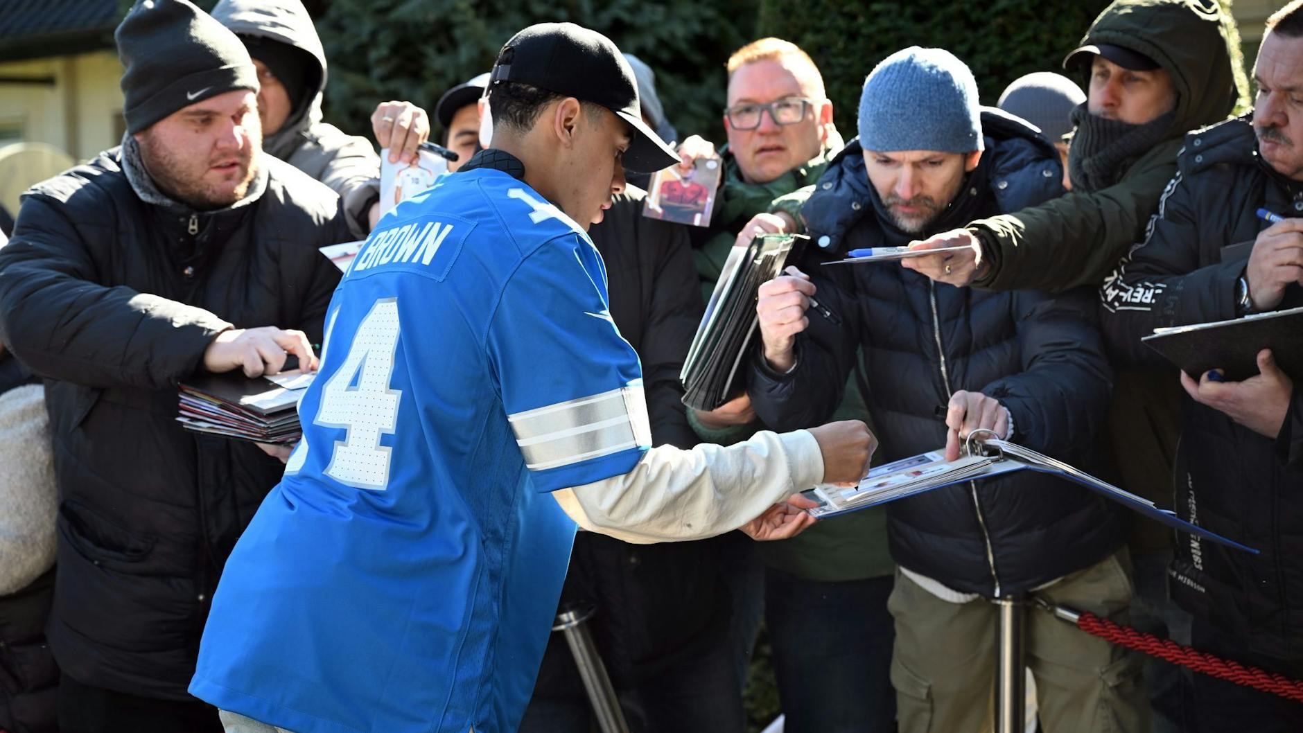 Jamal Musiala kommt in einem Amon-Ra-St.-Brown-Trikot am Teamhotel der Nationalmannschaft an, schreibt noch einige Autogramme.