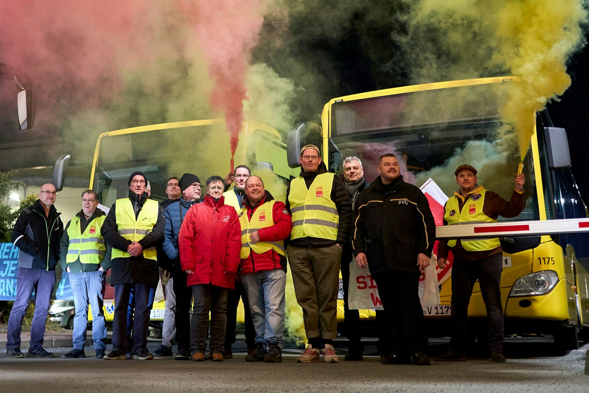 Mit Leuchtfackeln stehen streikende BVG-Mitarbeiter vor einem Bus-Betriebshof. Die Stimmung ist geladen.