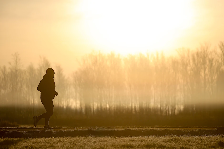 Ein Jogger ist am Morgen im Gegenlicht der Sonne unterwegs, während sich der Himmel durch Saharastaub gelb verfärbt hat.