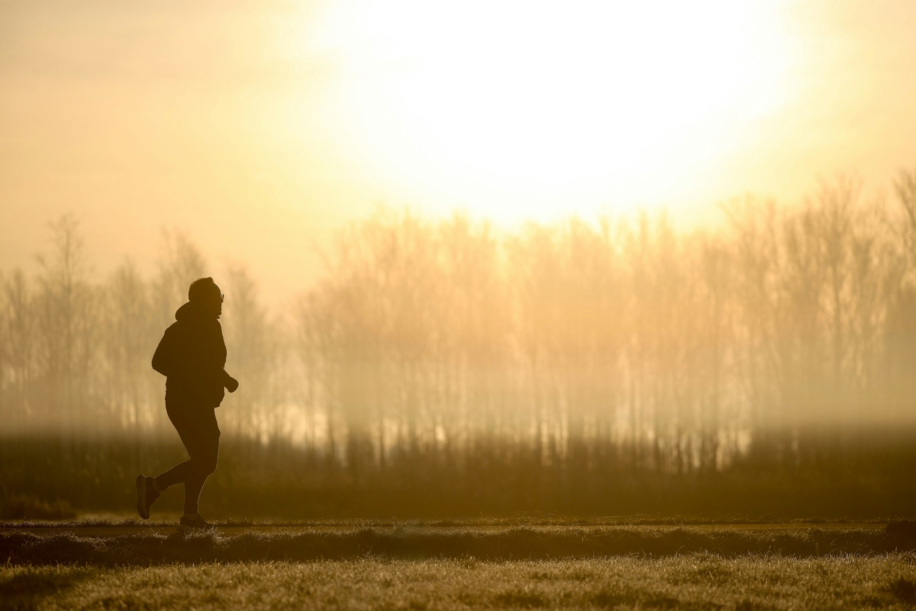Ein Jogger ist am Morgen im Gegenlicht der Sonne unterwegs, während sich der Himmel durch Saharastaub gelb verfärbt hat.