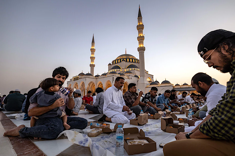 Gläubige beim abendlichen Fastenbrechen während des Ramadan vor einer Moschee im Emirat von Sharjah, VAE.